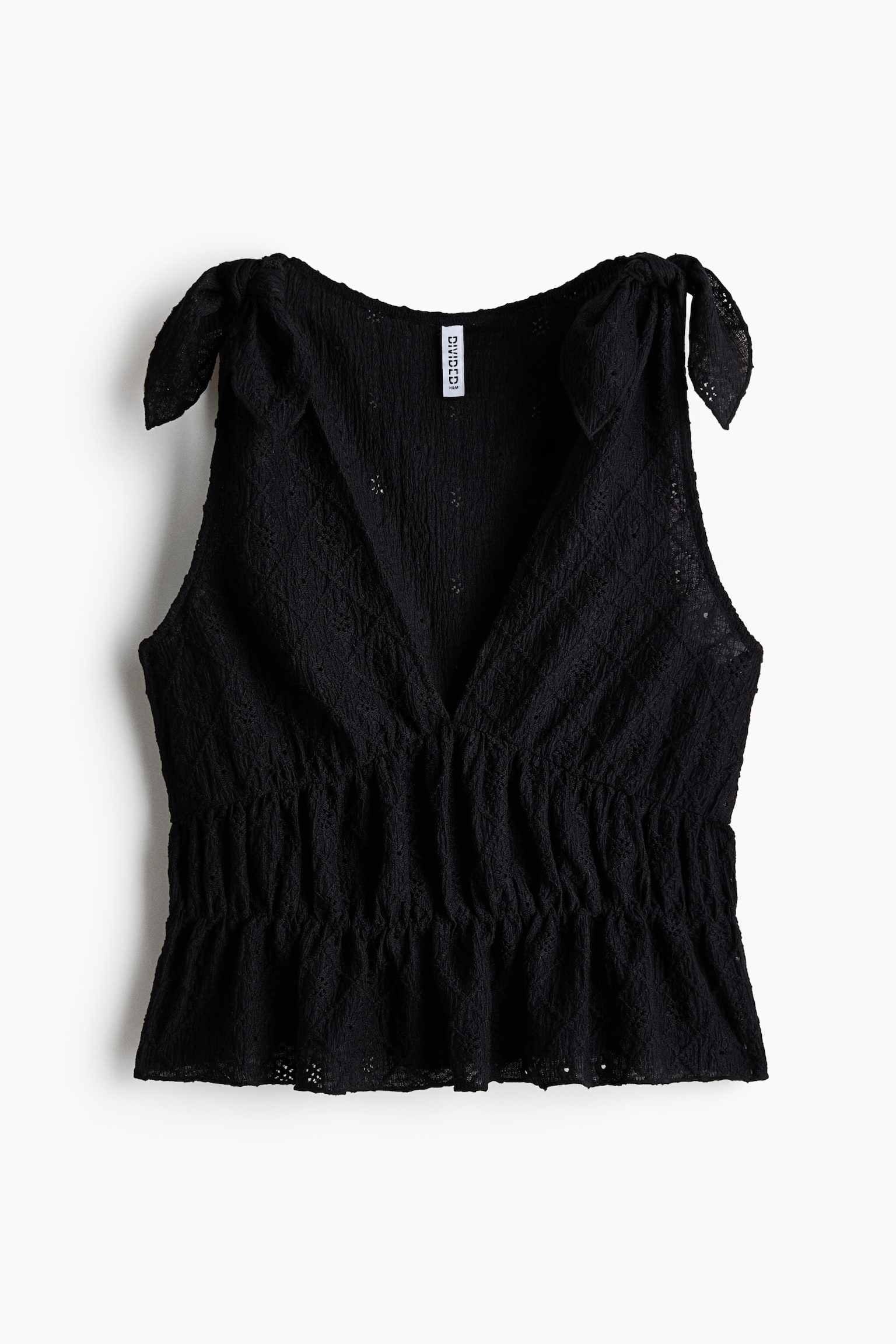 A black sleeveless top is displayed from the front, featuring tie-shoulder straps that form bows at the shoulders. It showcases a deep V-neckline and a crinkled eyelet patterned fabric, with a shirred waist creating a gathered peplum hem. - 1