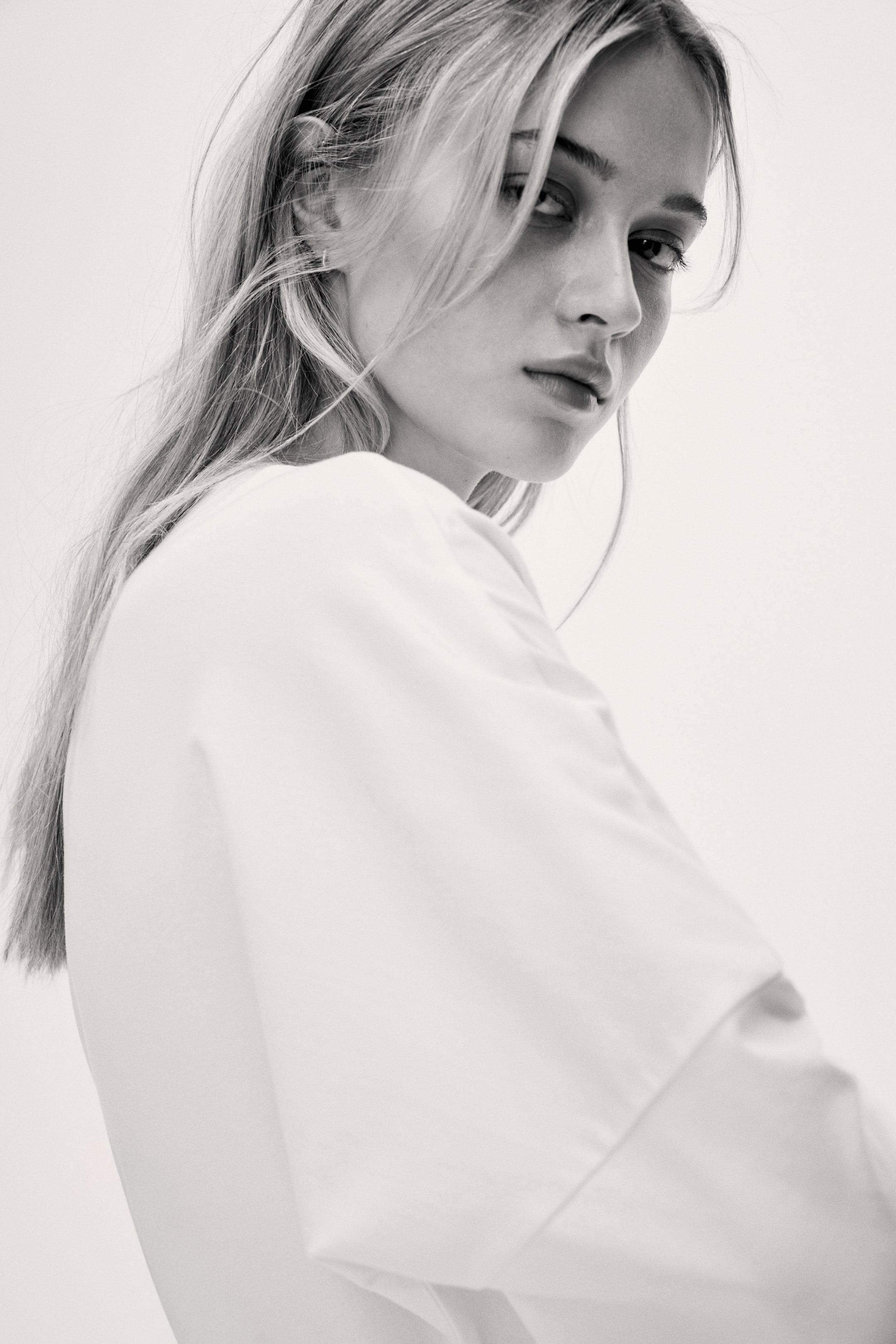 View larger image: A white, smooth-textured top drapes with a relaxed fit over the left shoulder, showcasing a visible seam along the shoulder line.