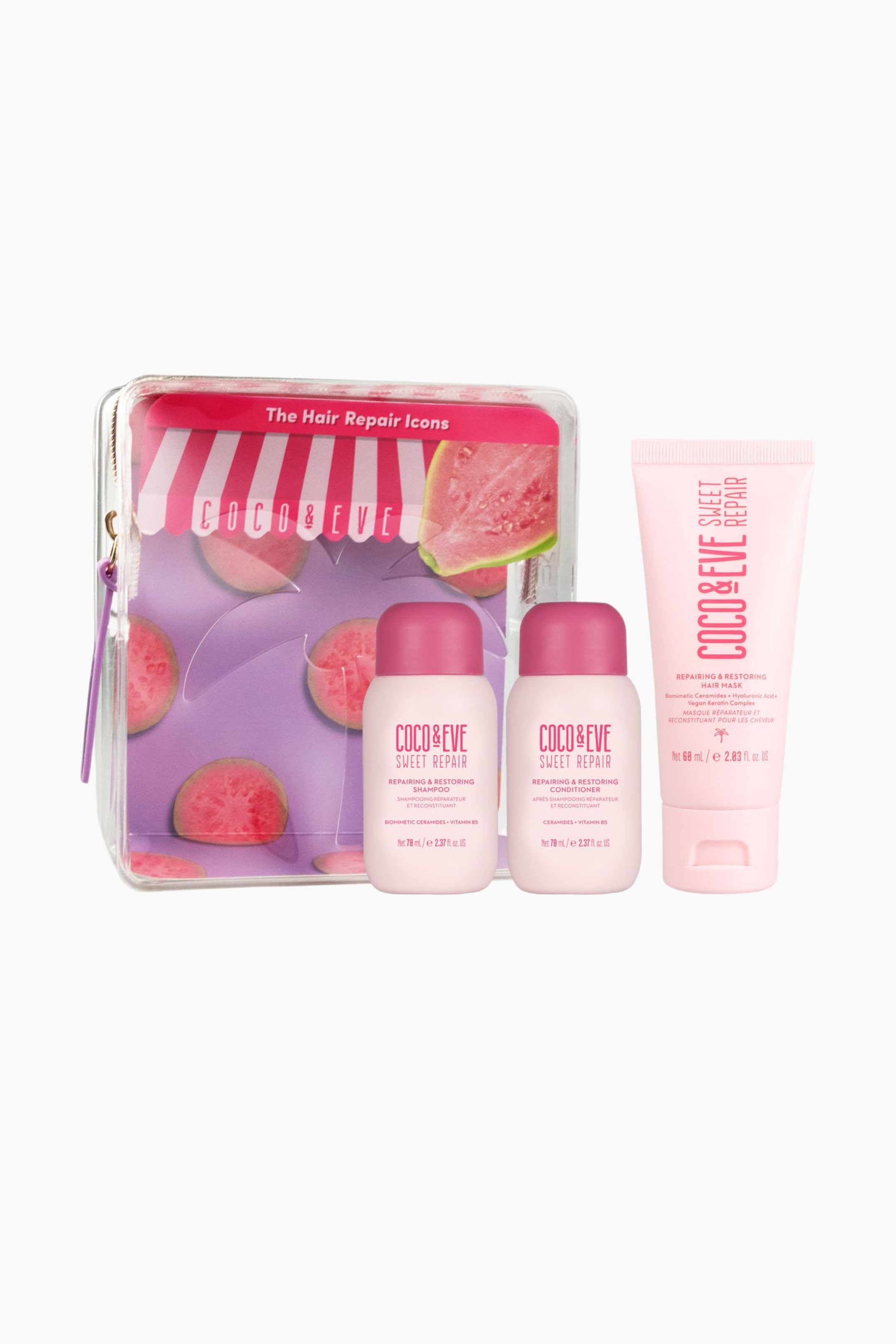 Se større billede: Et Coco & Eve Sweet Repair-rejsesæt står oprejst og fremviser en gennemsigtig lynlåspose med et guava-design i lilla og pink sammen med to små lyserøde flasker med mørkrosa låg og en matchende lyserød tubebeholdning. Alle produkter vender fremad og viser deres produktlabels med pink skrift.