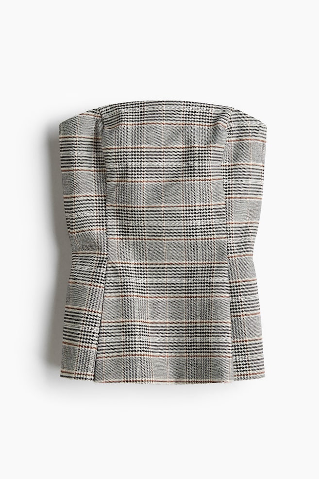 A bustier top is presented from the FRONT, featuring a woven plaid fabric in shades of grey, black, and white with subtle brown accents. Shaping seams are transitioning into knife pleats, creating a flared silhouette towards a gently rounded hem. - 1