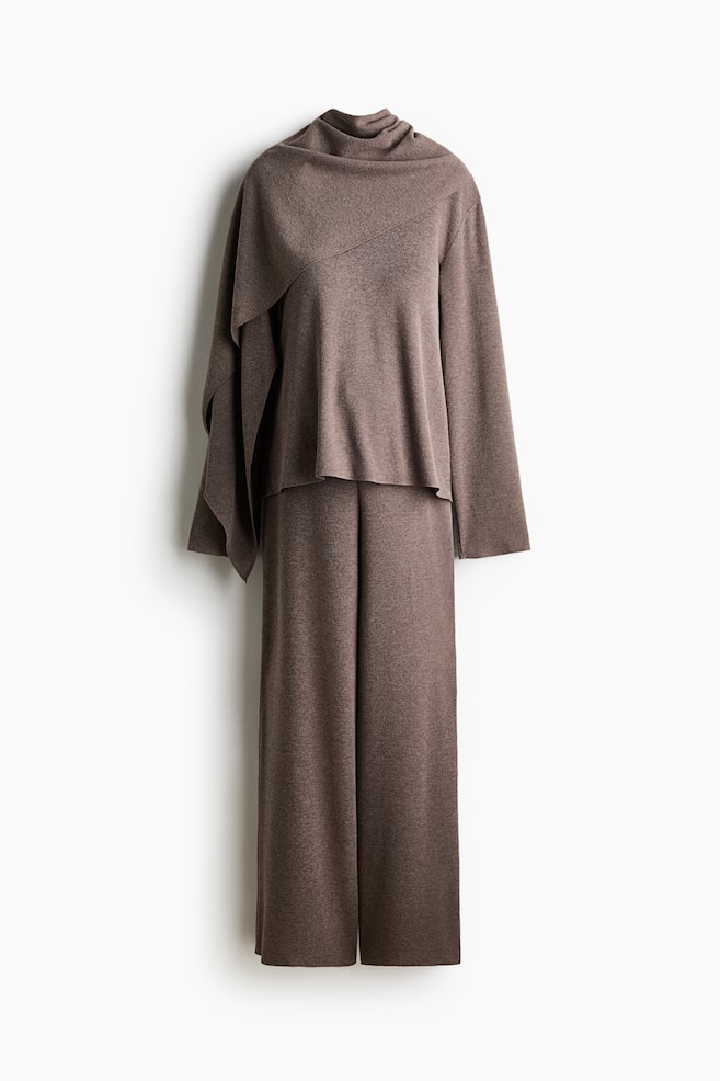 A brown knit matching set is shown facing front, featuring a long-sleeve top with an asymmetric draped scarf detail wrapping around the neck and cascading down the side. The top is layering over matching, relaxed-fit wide-leg trousers made from the same fine-knit material. - 1