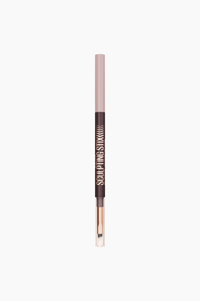 En dobbeltsidig sminkestift står oppreist og vender rett frem. Den øverste delen er lys rosa og går over i en mørk brun midtdel som viser "SCULPTING STIX" i rosegullskrift med pildesign, og bunnenden avslører en børsteapplikator med lyse børstehår og en ferrule i rosegull, dekket av en gjennomsiktig hette. - 1