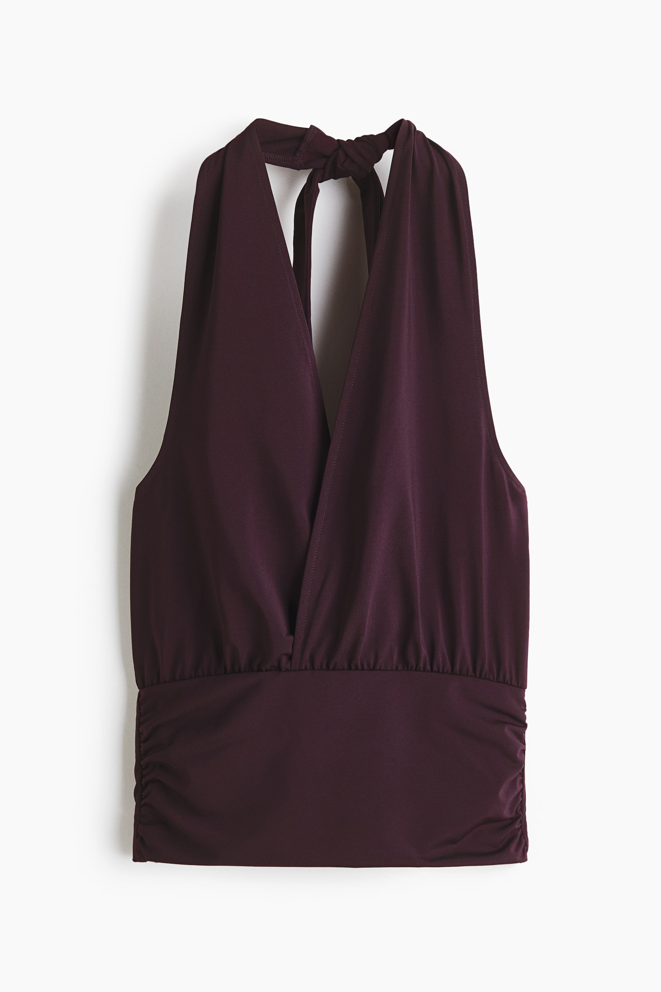 Προβολή μεγαλύτερης εικόνας: Ένα σκούρο μωβ τοπ με λαιμόκοψη halter, διαθέτει βαθιά V-λαιμόκοψη στο μπροστινό μέρος και δετή λωρίδα halter στο πίσω μέρος του λαιμού. Το μπούστο συγκεντρώνεται σε μια ελαστική ζώνη με λεπτομέρειες σούρας κατά μήκος των πλαϊνών ραφών.