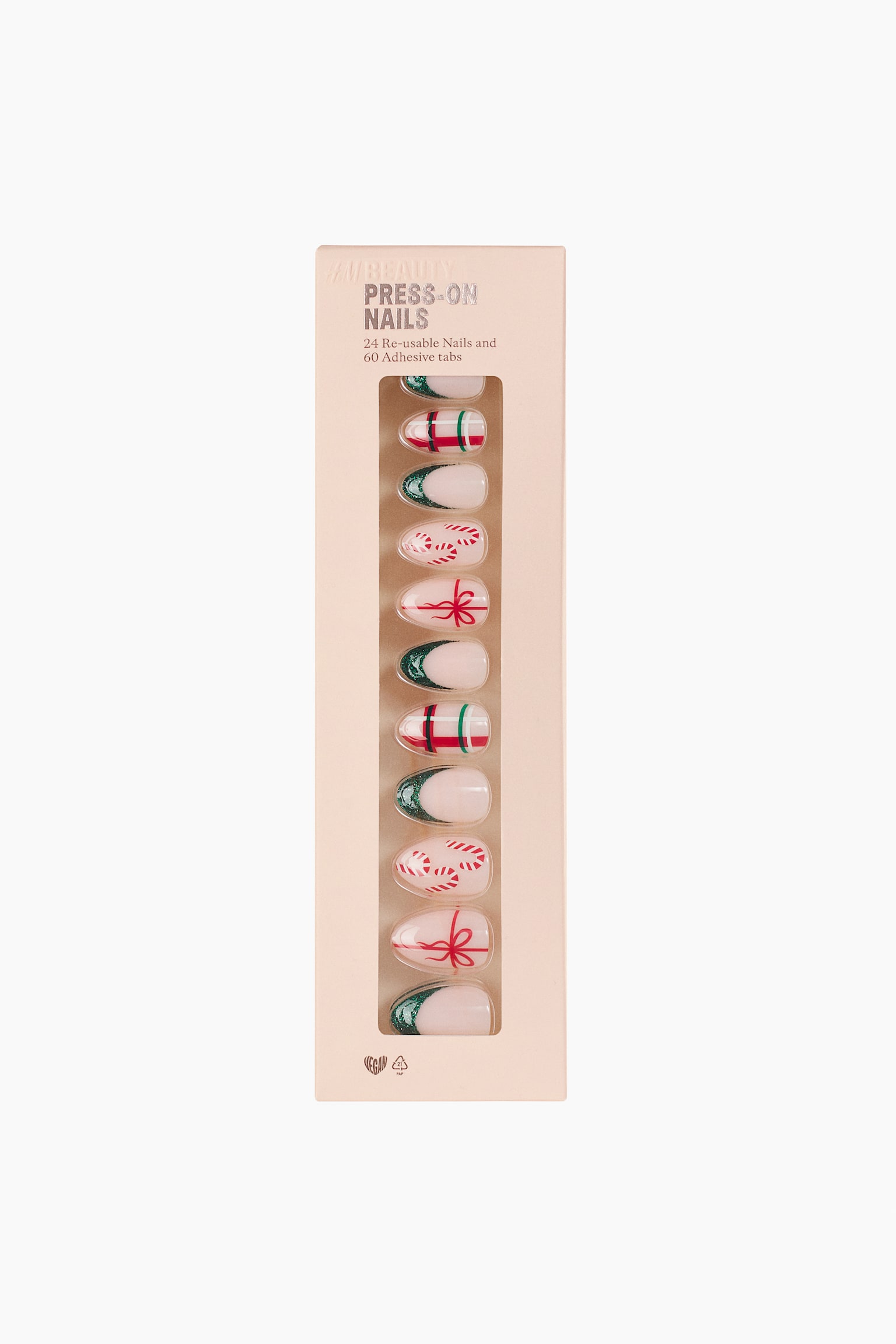 A set of press-on nails is displayed from the front in a light pink rectangular box with a clear window. The almond-shaped nails feature a variety of designs, including green glitter French tips, red and green tartan patterns, red bows, and candy canes.