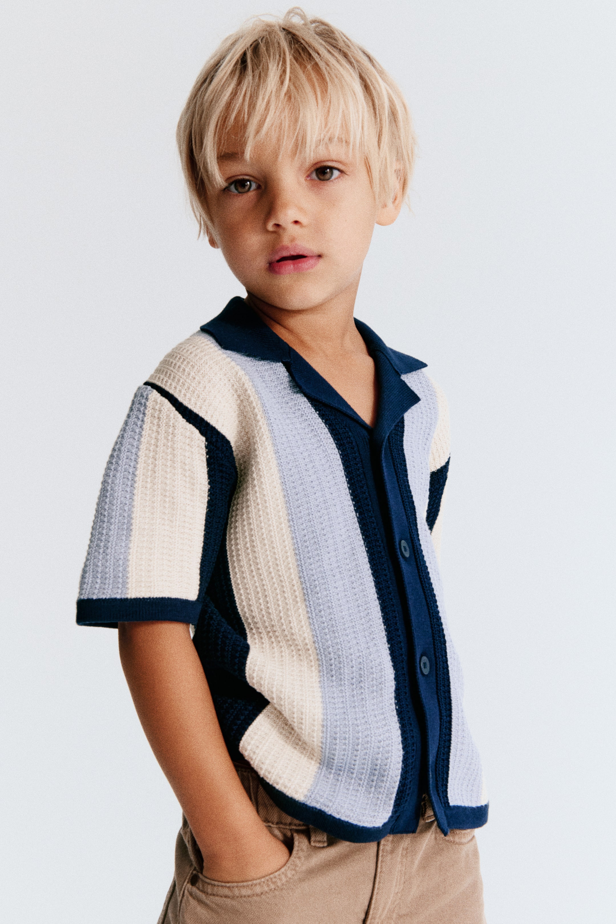 View larger image: A short-sleeved, textured-knit cotton shirt features vertical color-blocked stripes in navy blue, light blue, and cream. Shown from the front at a three-quarter angle, the shirt highlights a navy blue ribbed resort collar, a button-down front, and narrow ribbed trims at the cuffs and hem.