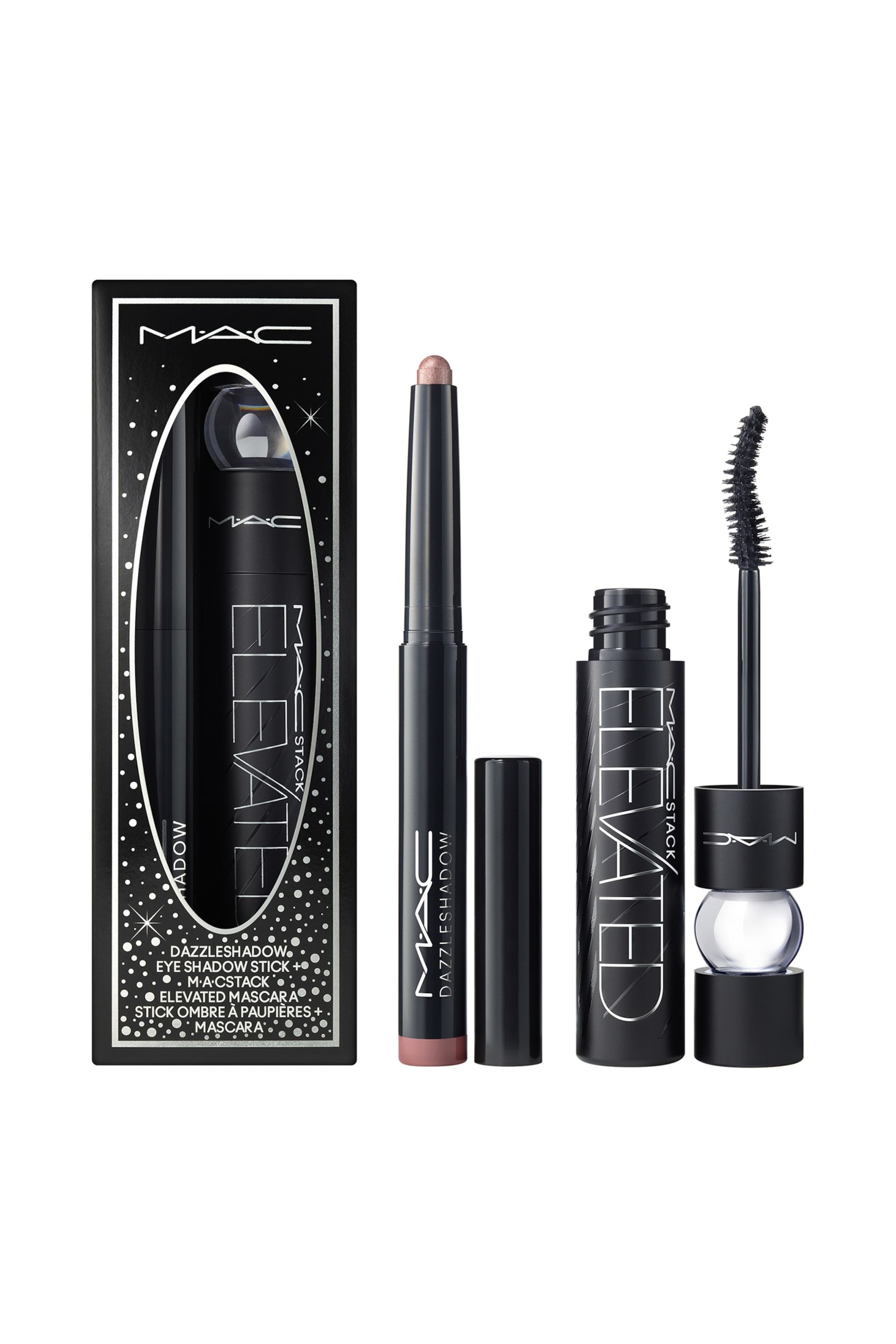 Visa större bild: Dressed To Dazzle Eye Duo visas i en svart dekorativ ask med ett ovalt fönster tillsammans med sina två makeup-produkter. Intill asken står en smal svart ögonskuggssticka utan lock, med en skimrande roséguldig spets synlig och locket bredvid, medan en öppen svart mascaratub visar sin böjda borste med en genomskinlig sfärisk detalj.