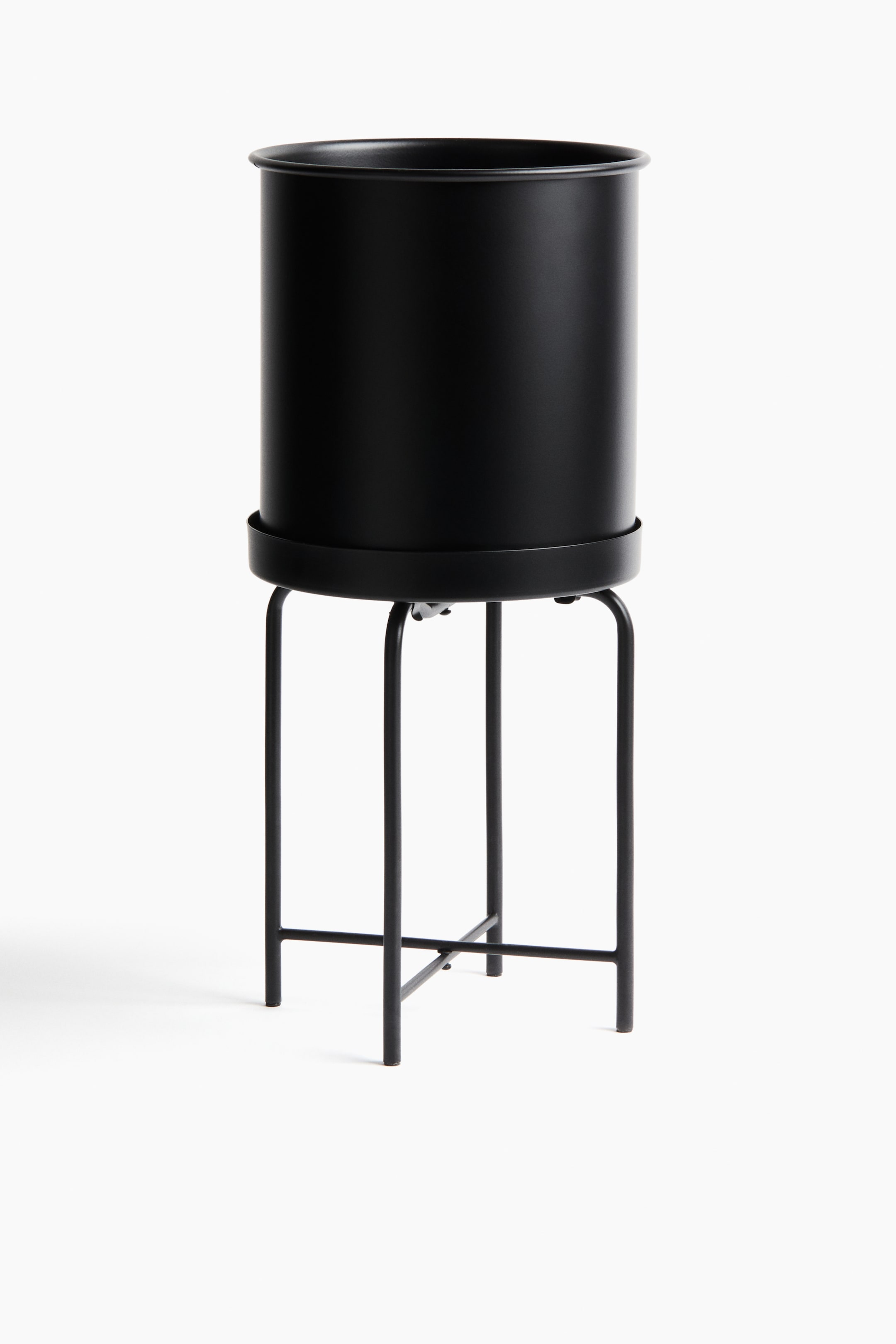 이미지 확대 보기: 검은색 원통형 화분이 둥글게 말린 테두리를 가지고 얕고 둥근 쟁반 안에 놓여 있습니다. 이 쟁반은 네 개의 얇은 다리가 교차 사이로 연결되어 아래쪽에 X 모양을 형성하는 검은 금속 스탠드에 의해 지탱되고 있습니다.