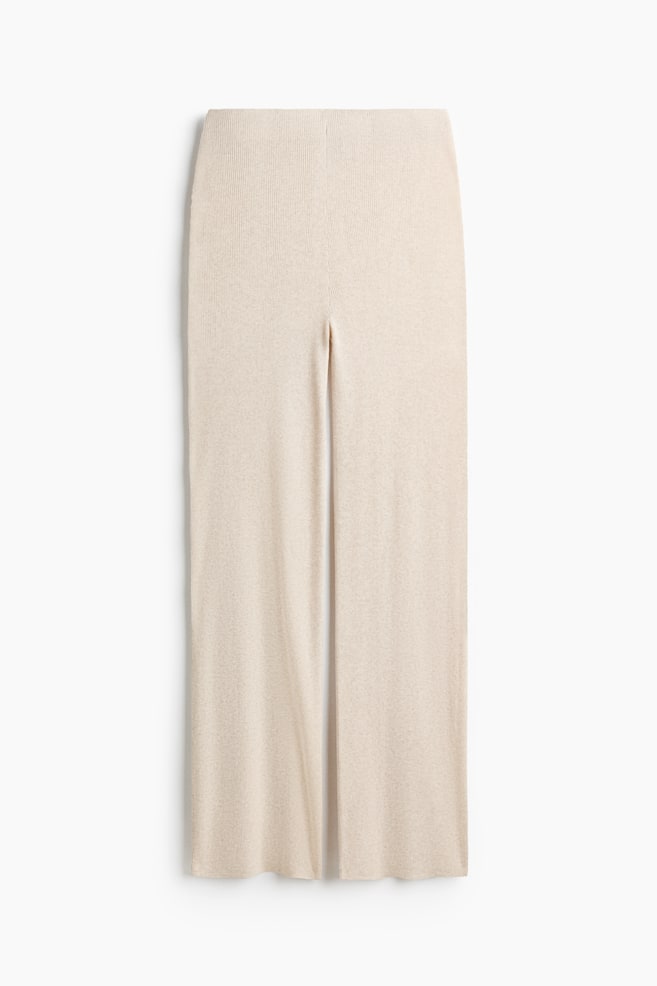 Pantalones ajustados de punto canalé en color beige claro, mostrados en una vista plana frontal. Presentan una cintura lisa y plana, y piernas rectas, cada una con una discreta costura central delantera. - 1