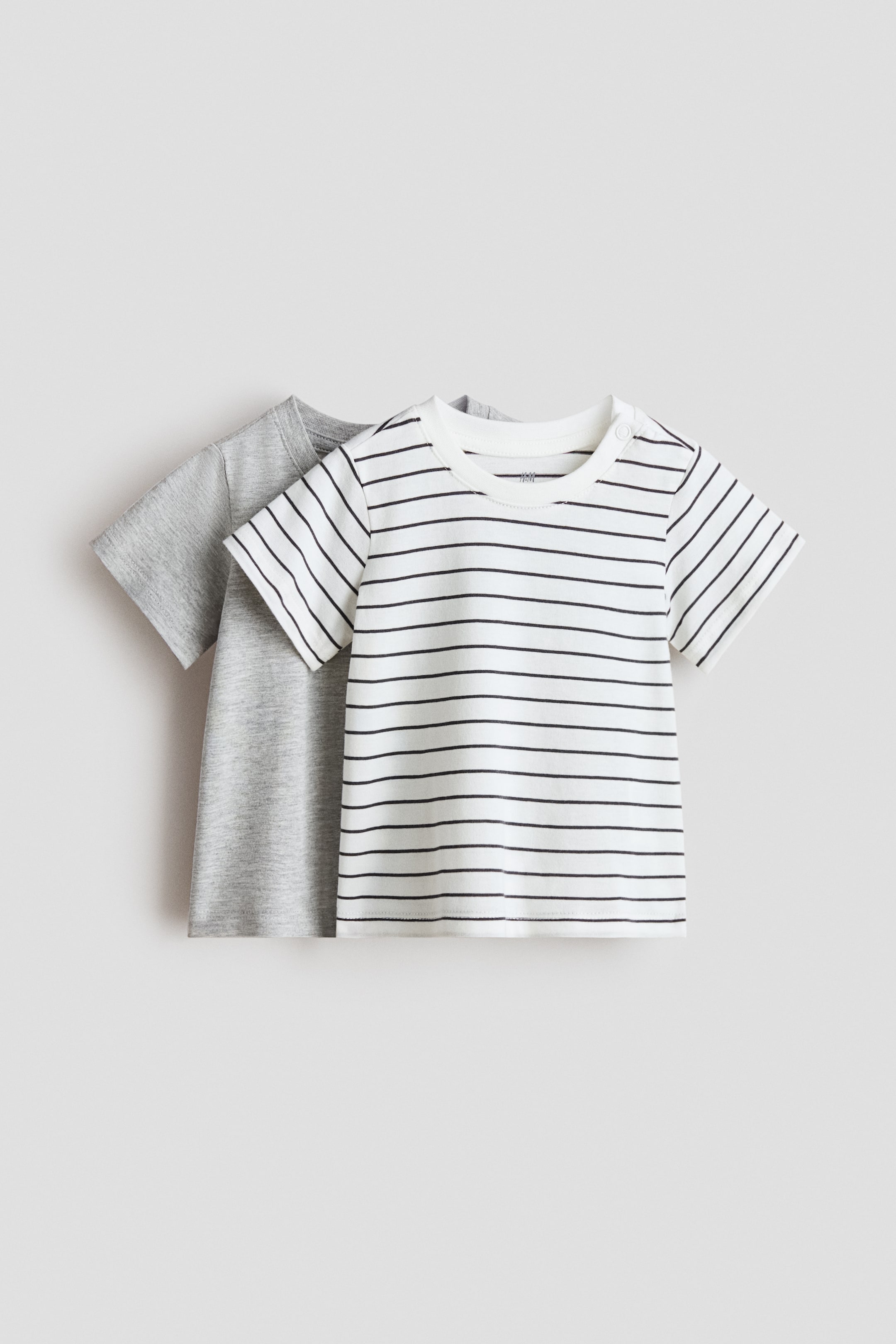 View larger image: A 2-pack of cotton T-shirts shown from the front. One T-shirt is a solid light grey, and the other is white with thin black horizontal stripes and two snap buttons on the left shoulder.