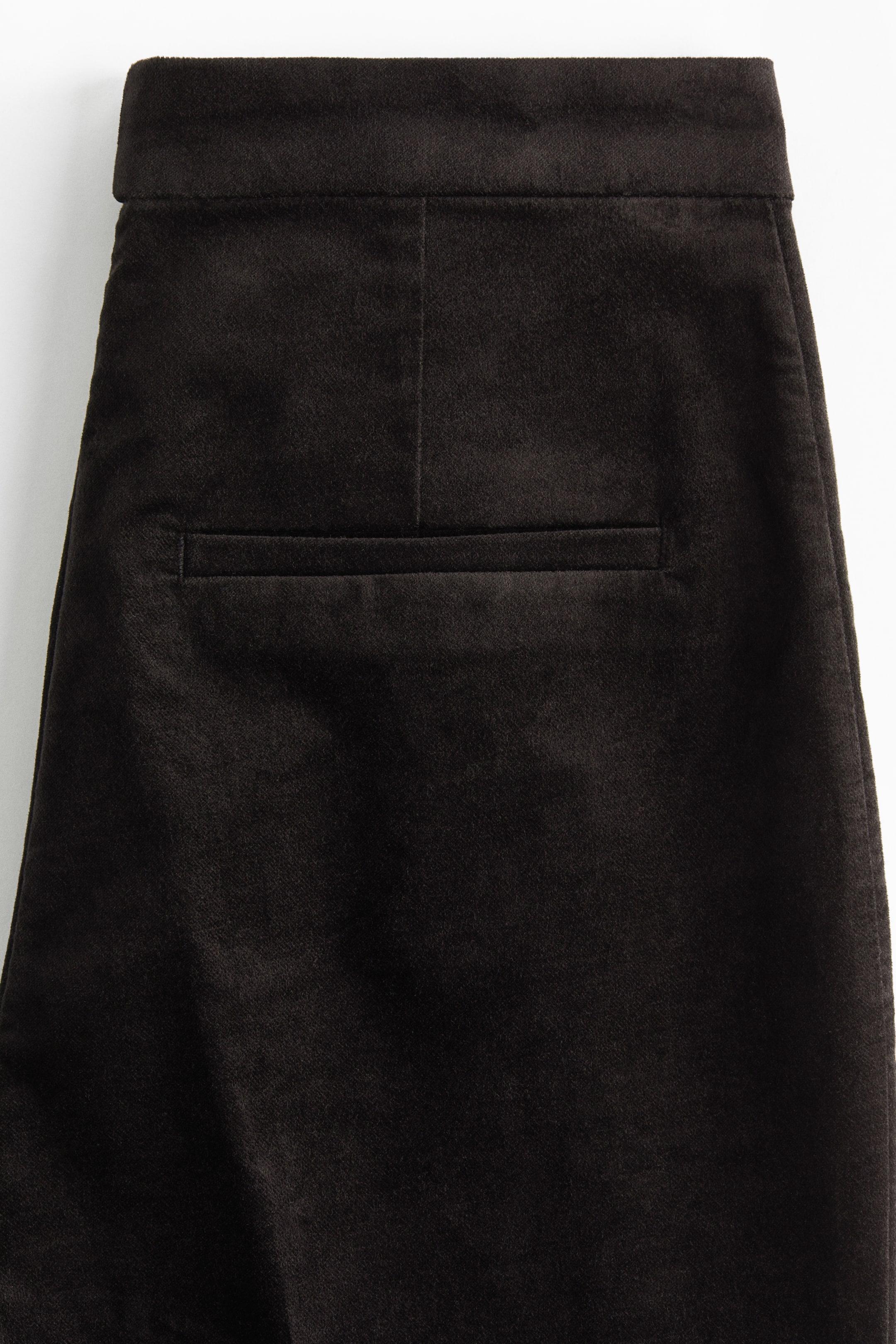 Ver imagen más grande: Pantalones de terciopelo marrón oscuro presentados desde atrás, con una cintura, una costura vertical central y un único bolsillo welt horizontal.