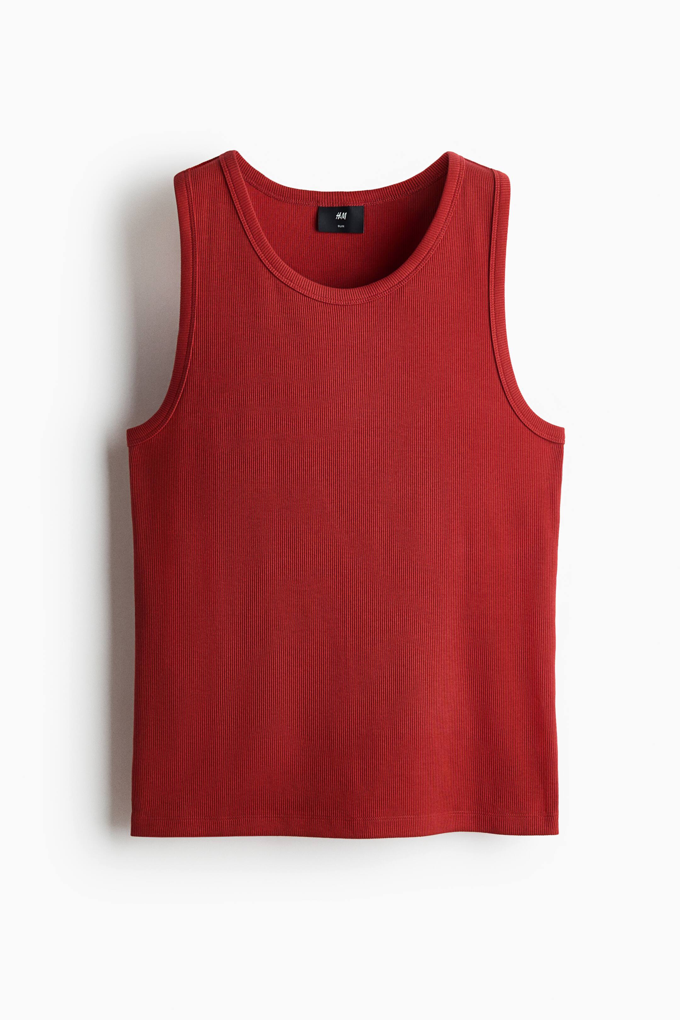 View larger image: A brick-red ribbed tank top is shown from the front, featuring a round neckline, a straight hem, and a small black brand label at the back of the neck.