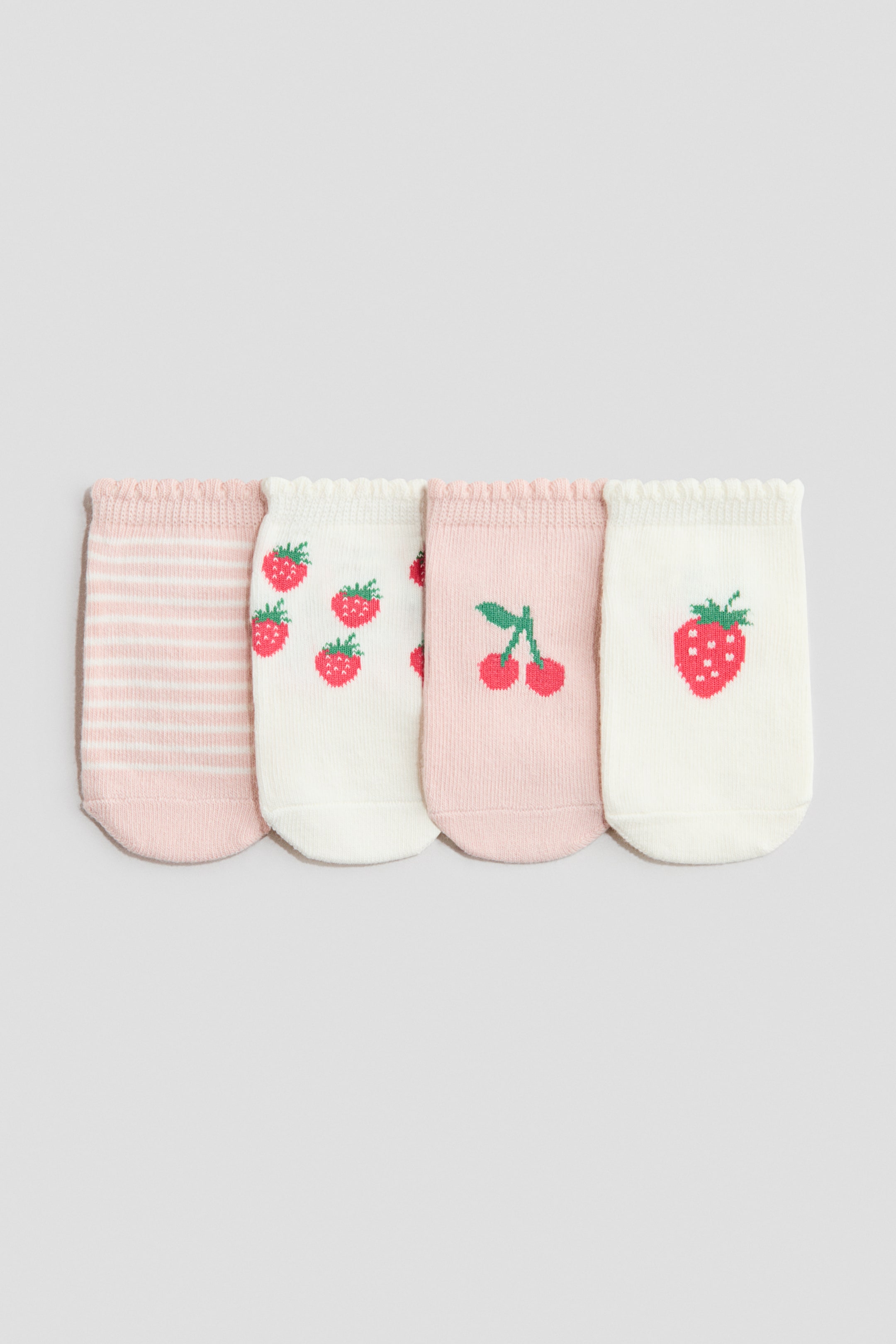 View larger image: Four socks are neatly lined up in a row, each showcasing a unique design and ruffled cuff from the front. The first sock boasts pink and white horizontal stripes, while the remaining three highlight delightful fruit patterns: an array of red strawberries on white, vibrant red cherries on pink, and a prominent red strawberry on white.