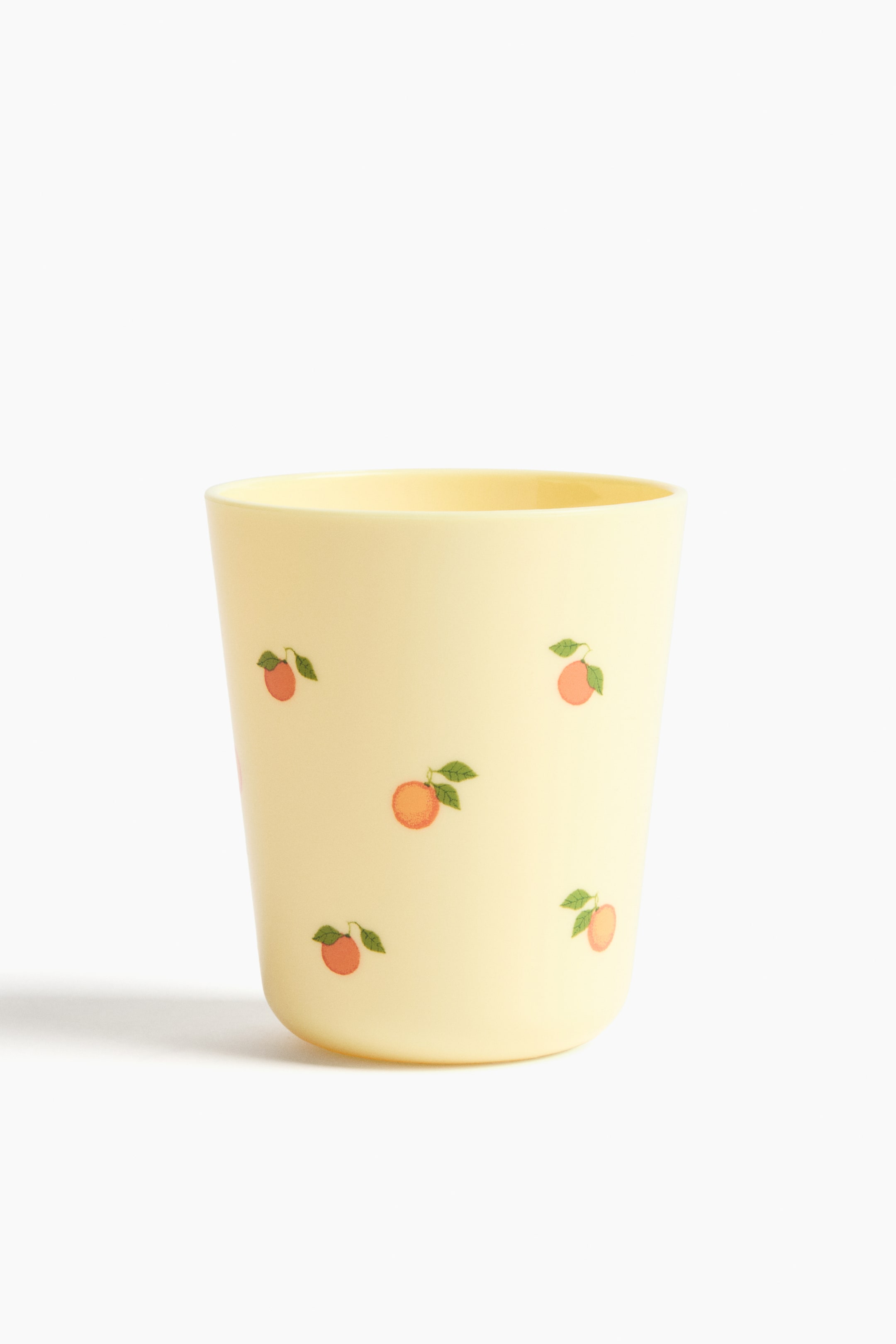 Agrandir l'image: Une tasse en plastique jaune clair est présentée, ornée d'un motif répétitif de petits fruits orange avec des feuilles vertes sur toute sa surface.