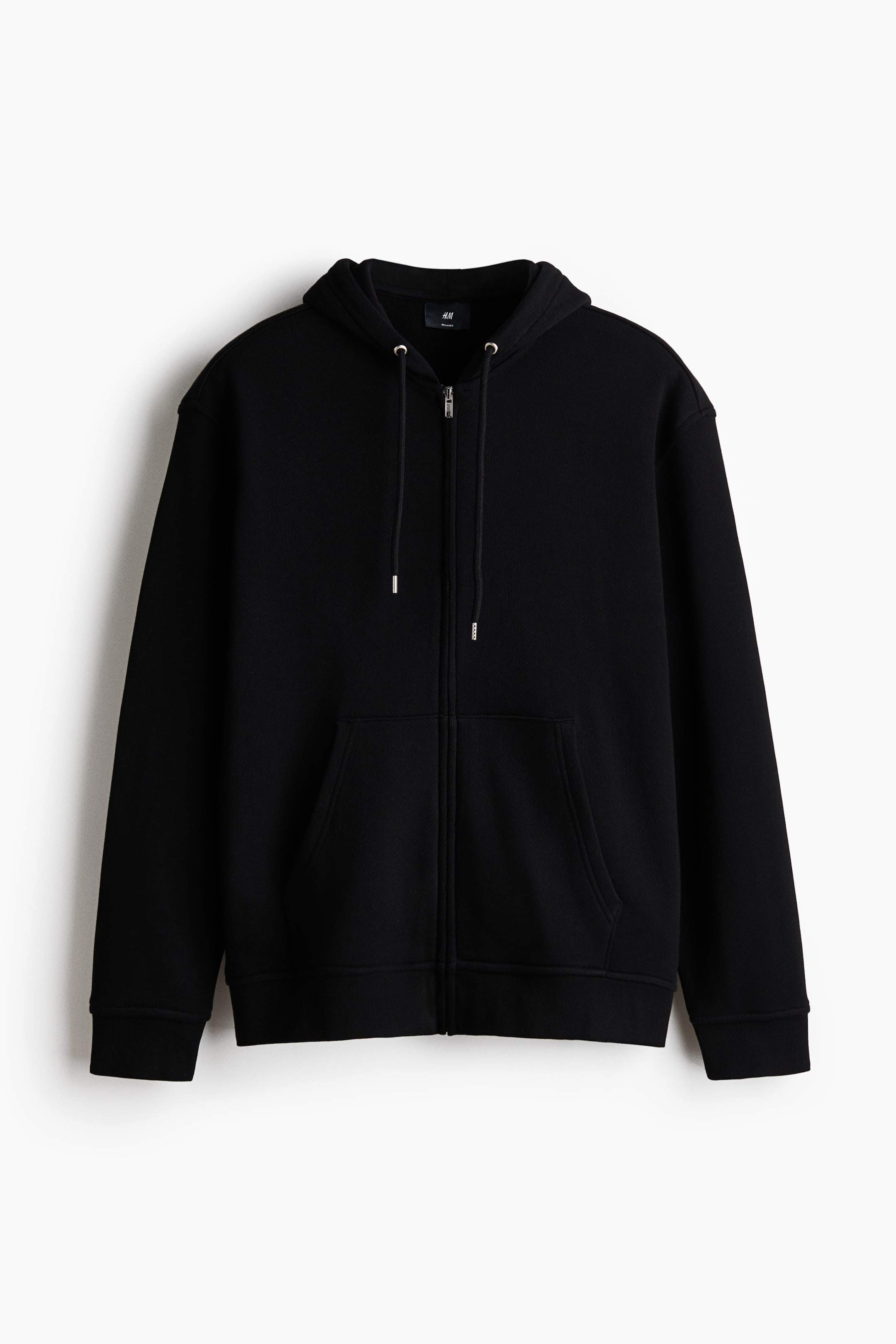 Xem ảnh lớn hơn: Một chiếc áo hoodie màu đen có khóa kéo phía trước, được hiển thị từ phía trước, nổi bật với mũ trùm đầu có dây rút, khóa kéo bạc phía trước và túi vá phía trước. Nó có vai rủ, tay áo dài với cổ tay áo bo gân và gấu áo bo gân, mang lại dáng vẻ thoải mái.