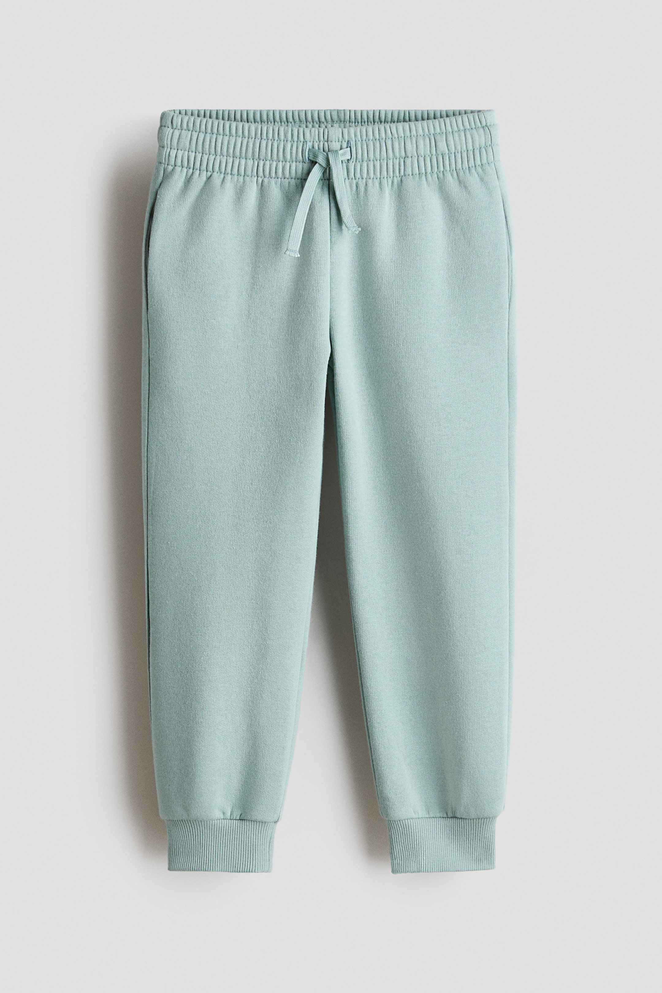 View larger image: Light blue joggers in sweatshirt fabric, featuring an elasticated drawstring waist with the drawstring tied at the FRONT, plus side pockets and ribbed cuffs at the hems.
