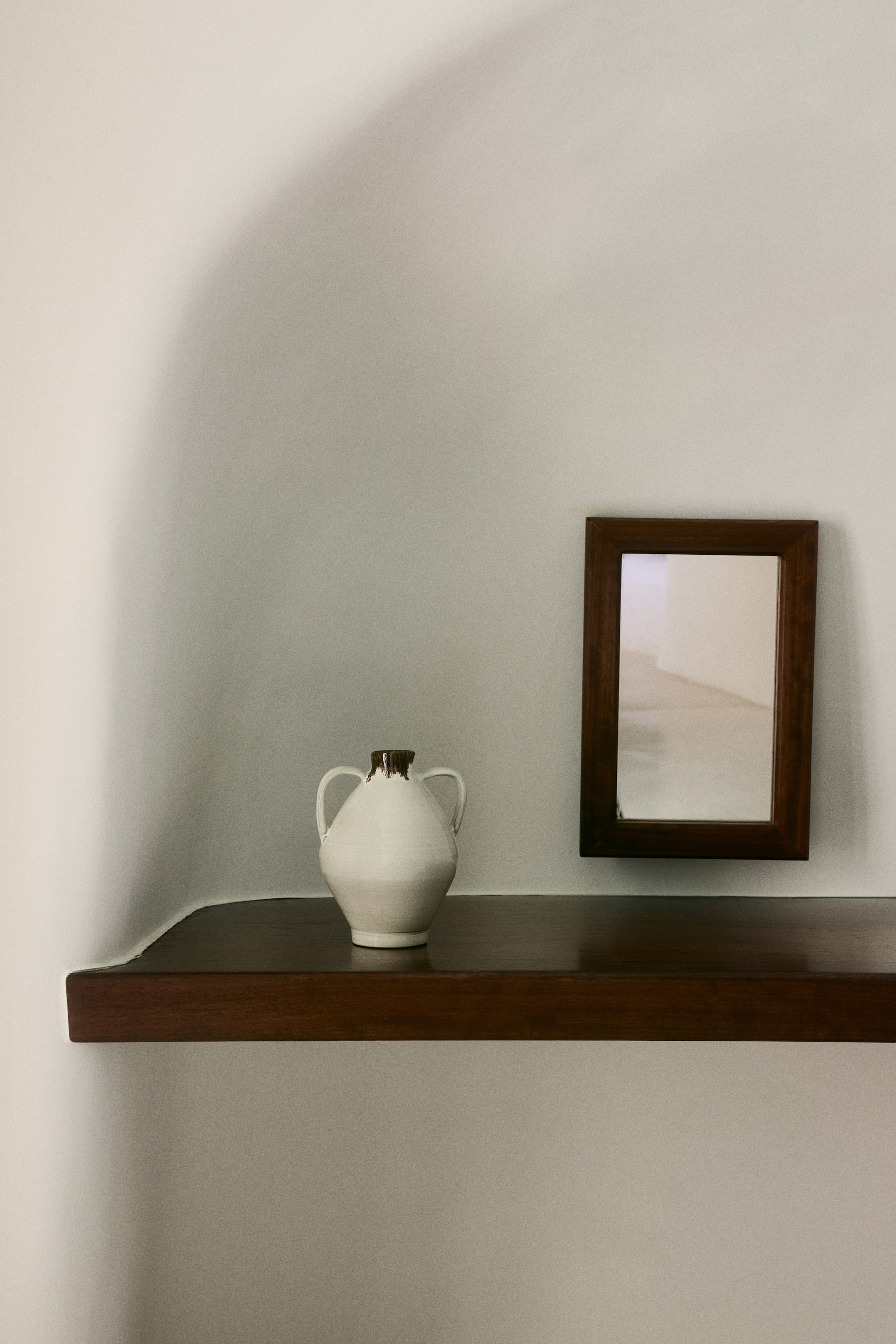 Zobacz większy obraz: Ceramiczny wazon prezentuje pękaty biały korpus, zwężającą się szyjkę i dwa wyraziste uchwyty. Jego krawędź wyróżnia się kontrastującym ciemnobrązowym szkliwem.