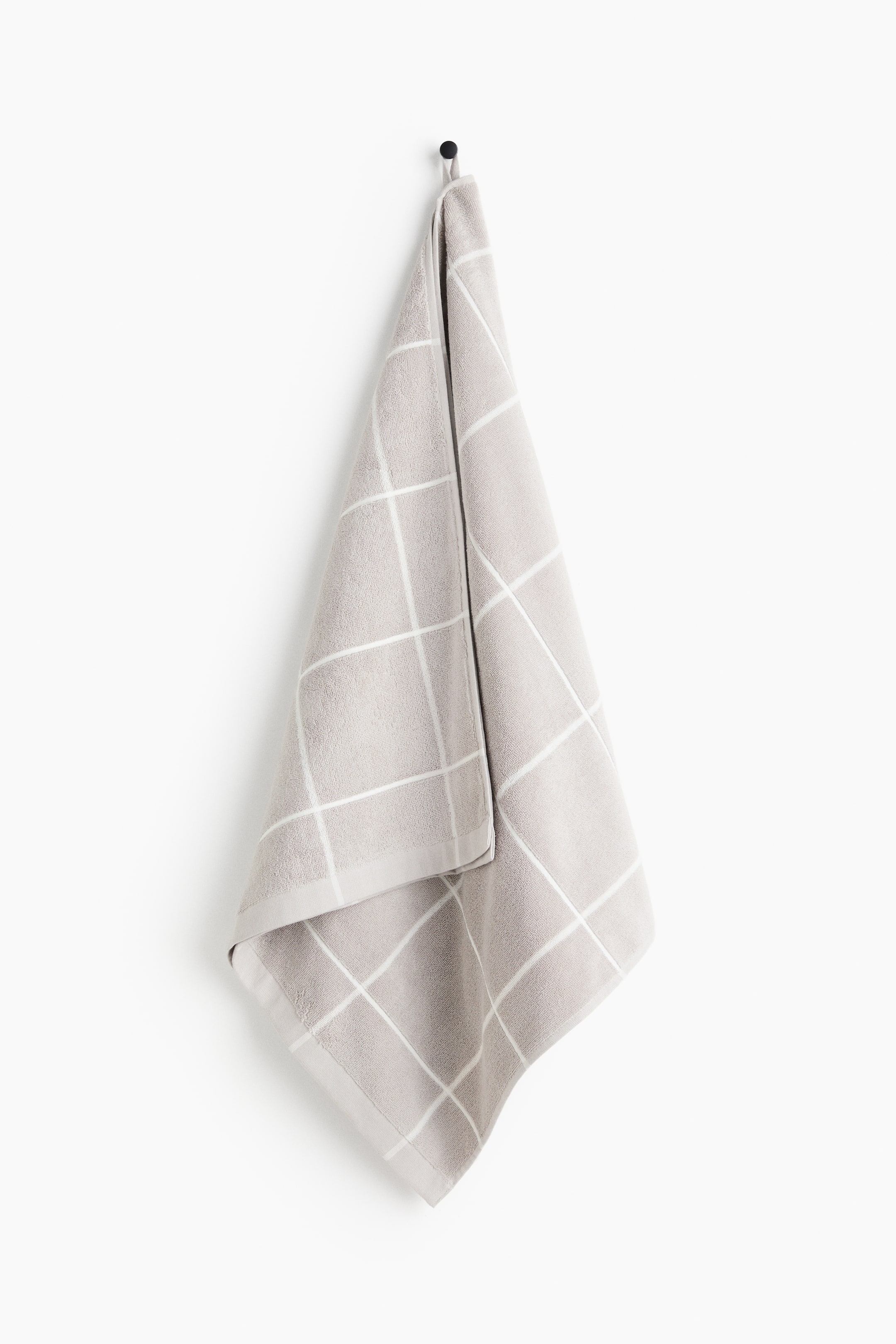 View larger image: The towel showcases a subtle grey shade adorned with a white grid design. It is neatly folded and displayed vertically.