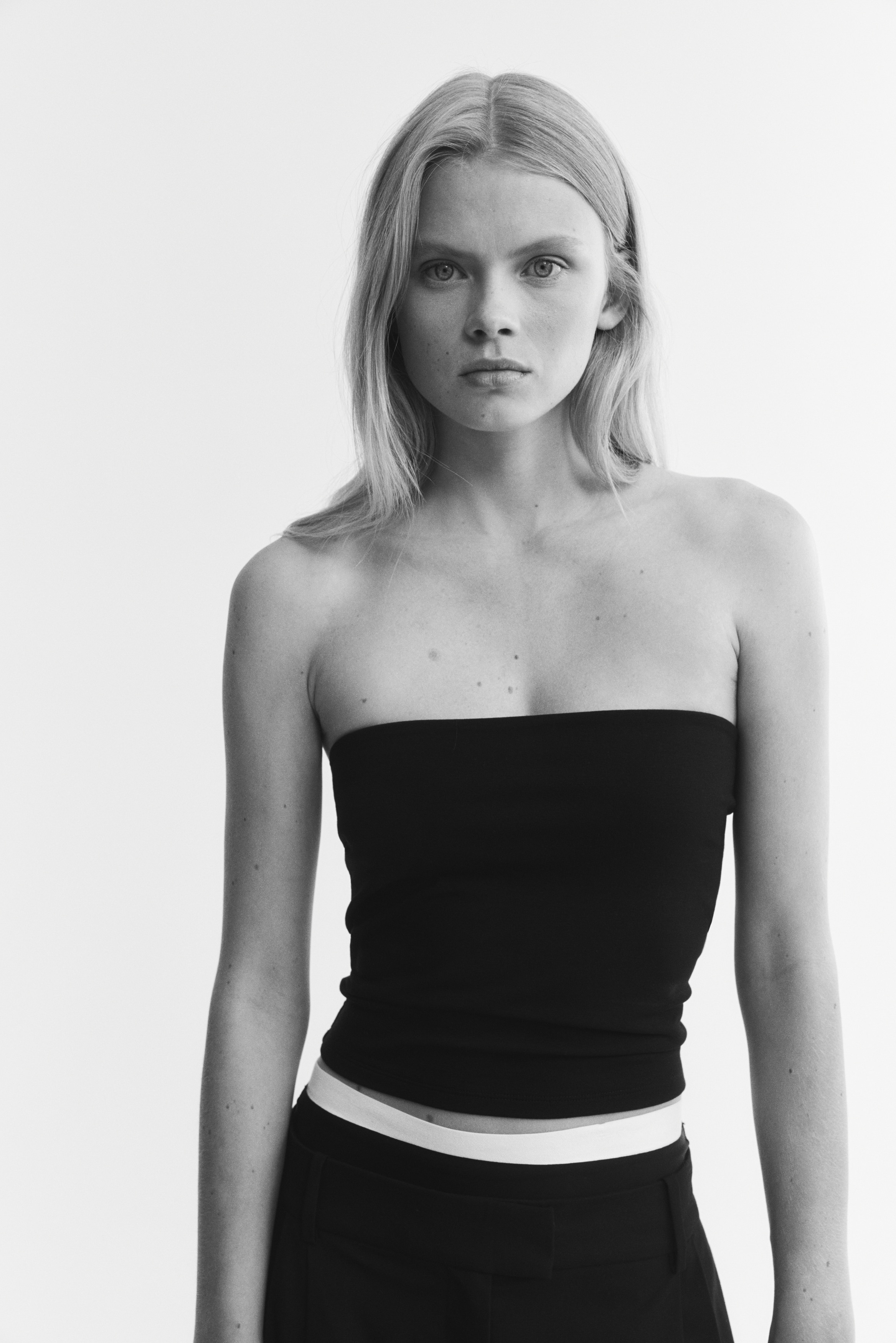A black bandeau top showcases a sleek, strapless design from a front perspective. It features a straight top edge and a straight hem.