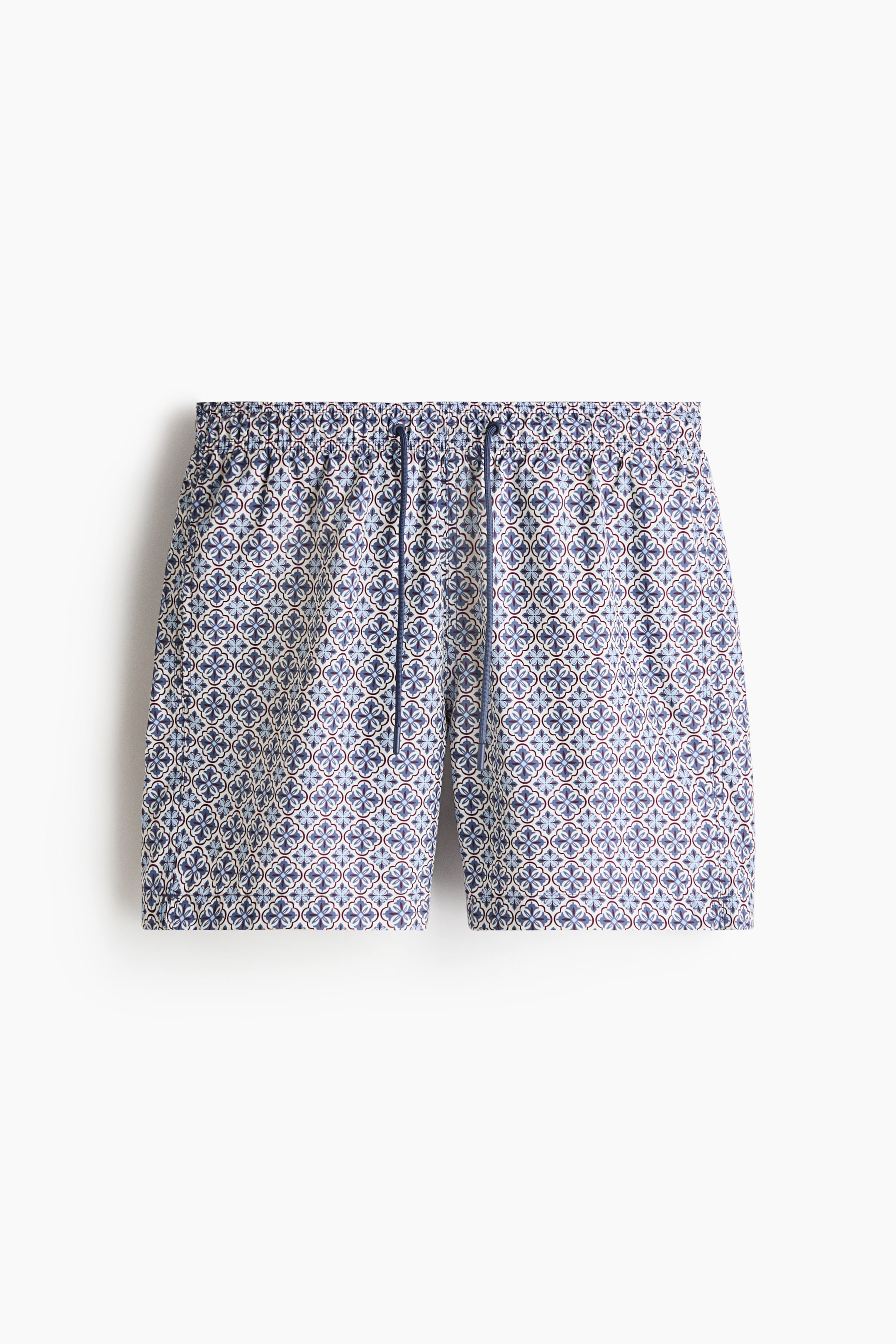 View larger image: Swim shorts are laid flat, featuring an all-over geometric pattern in white, blue, and brown, with an elasticized drawstring waistband.