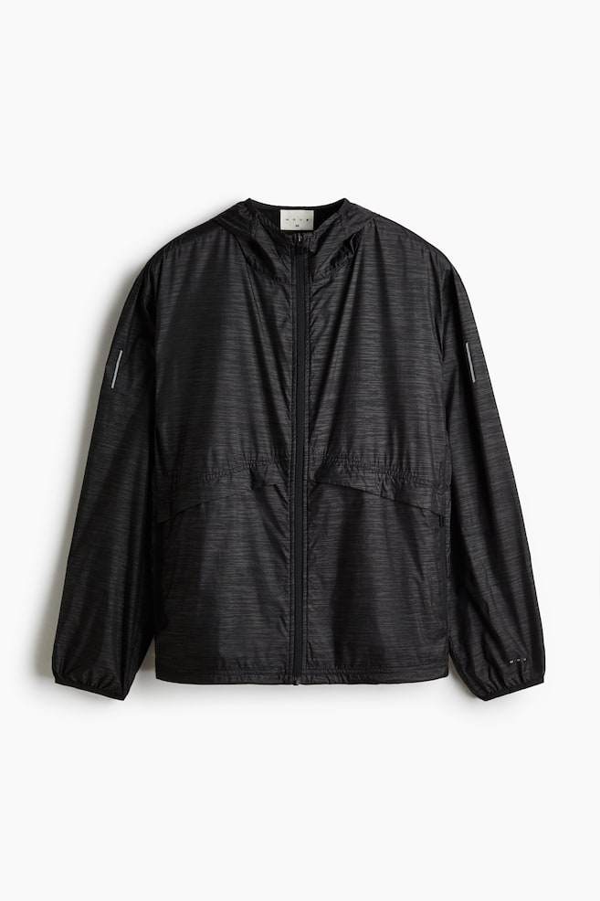 A black loose-fit running jacket is shown from the FRONT, featuring a subtle horizontal texture. It is displaying a hooded collar, a full zip closure down the front, dropped shoulders, long sleeves with elasticated cuffs, and horizontally zipped side pockets. White reflective lines are visible on the outer sleeves. - 1