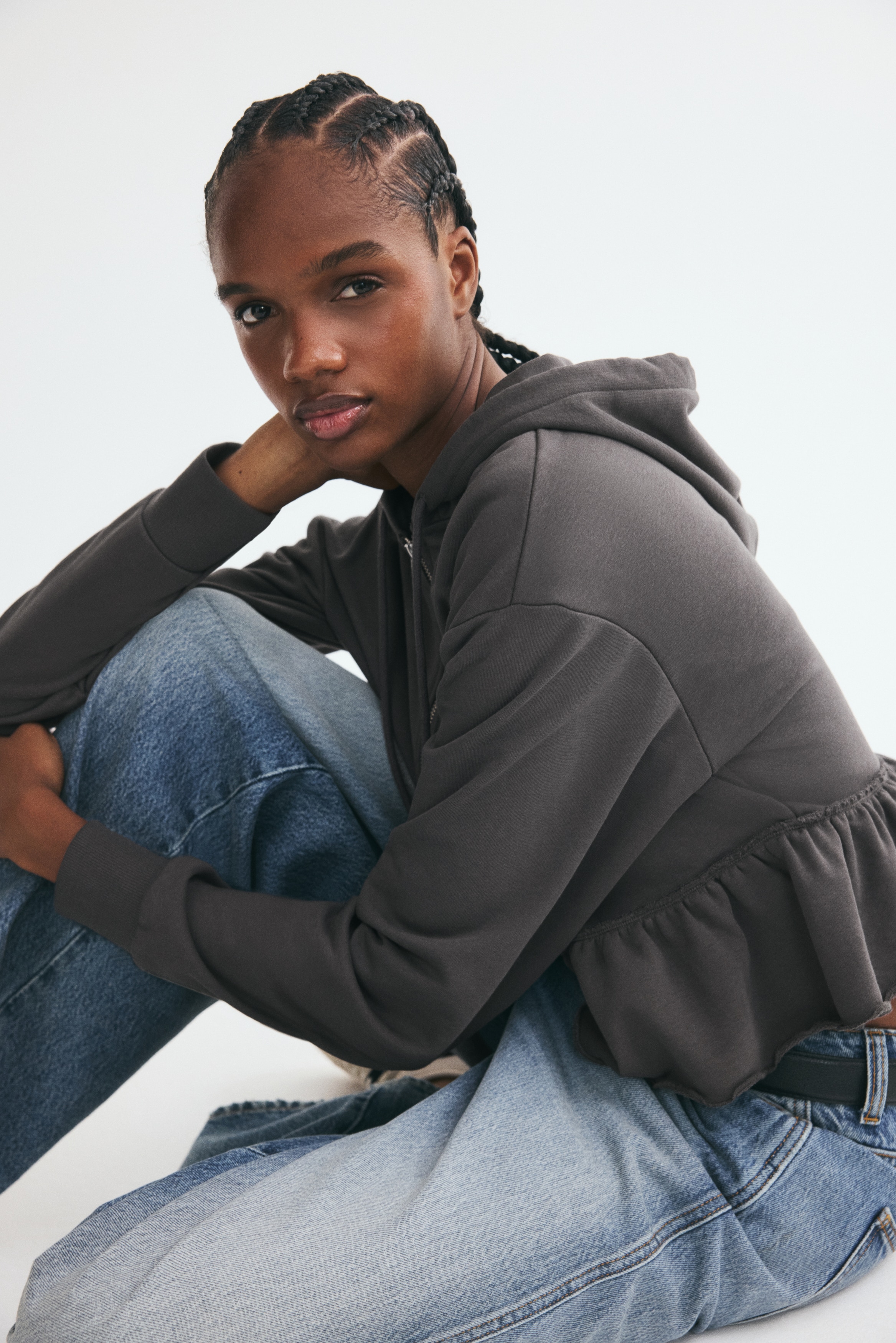 Má»t chiáº¿c Ã¡o hoodie khÃ³a kÃ©o mÃ u xanh bá»¥i ÄÆ°á»£c chá»¥p tá»« phÃ­a trÆ°á»c, vá»i mÅ© trÃ¹m cÃ³ dÃ¢y rÃºt, vai rÆ¡i vÃ  tay dÃ i vá»i cá» tay bo gÃ¢n. Trang phá»¥c cÃ³ ÄÆ°á»ng may nhÃºn á» eo, xÃ²e thÃ nh pháº§n peplum rá»ng vá»i gáº¥u Ã¡o ÄÆ°á»£c may váº¯t sá».