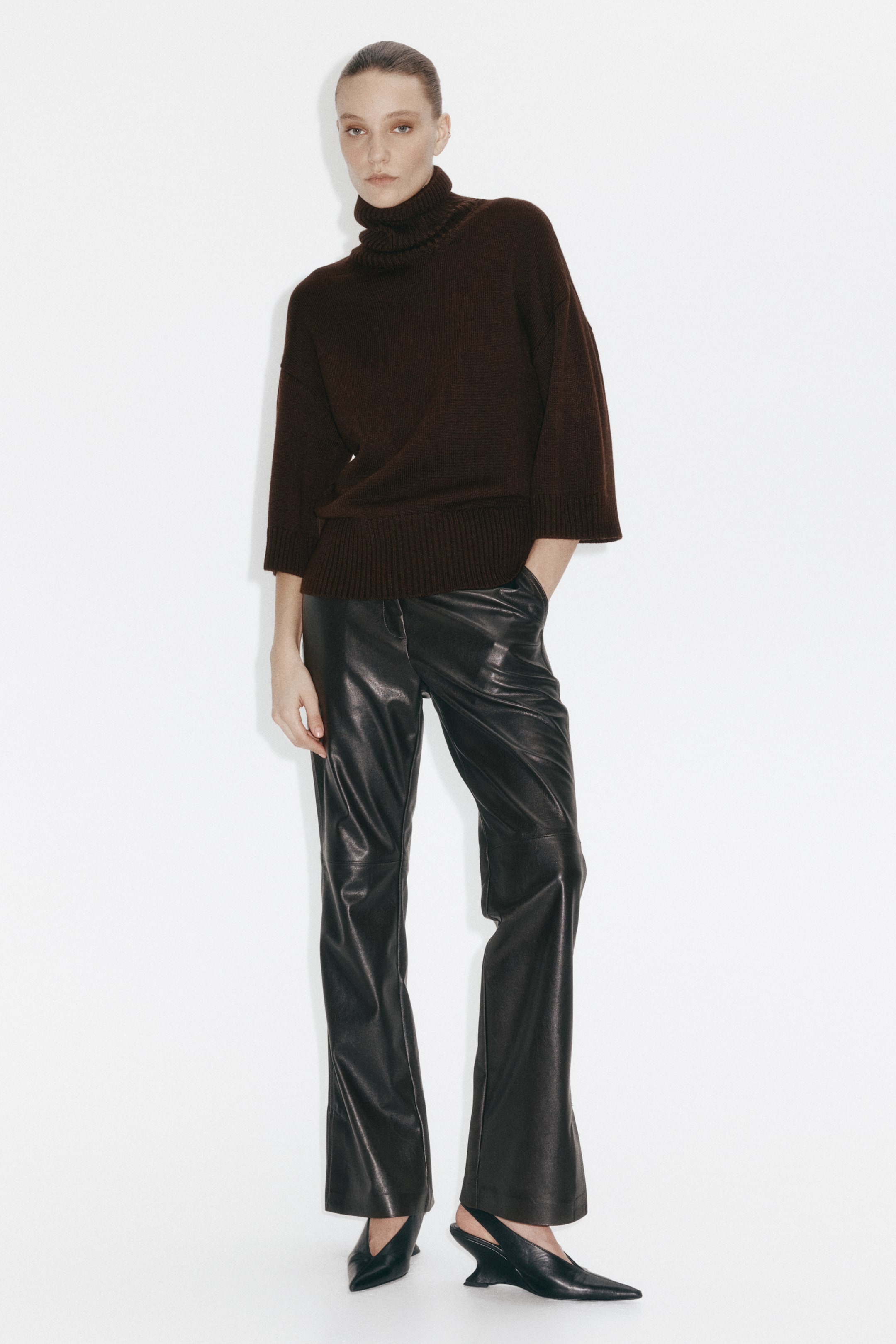 View larger image: A dark brown turtleneck sweater featuring a relaxed, oversized fit with wide three-quarter-length sleeves finished with ribbed cuffs. Designed with a folded turtleneck collar and a ribbed hem.