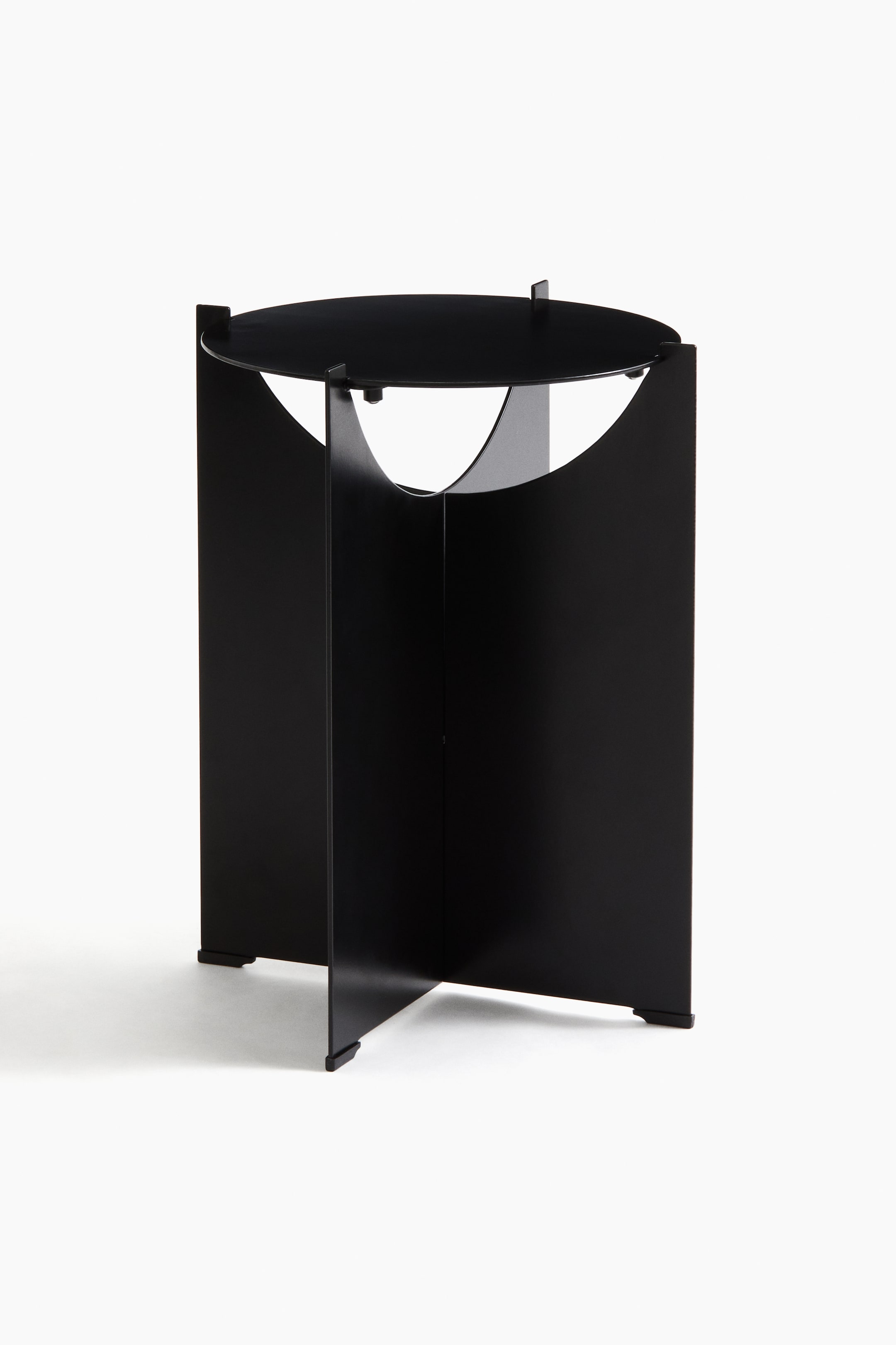 Größeres Bild ansehen: Ein schwarzer Beistelltisch aus Edelstahl steht frontal, mit einer runden Tischplatte und einem minimalistischen Design, das aus sich kreuzenden vertikalen Paneelen besteht, die die Basis bilden und nahe der Oberseite geschwungene Aussparungen aufweisen.