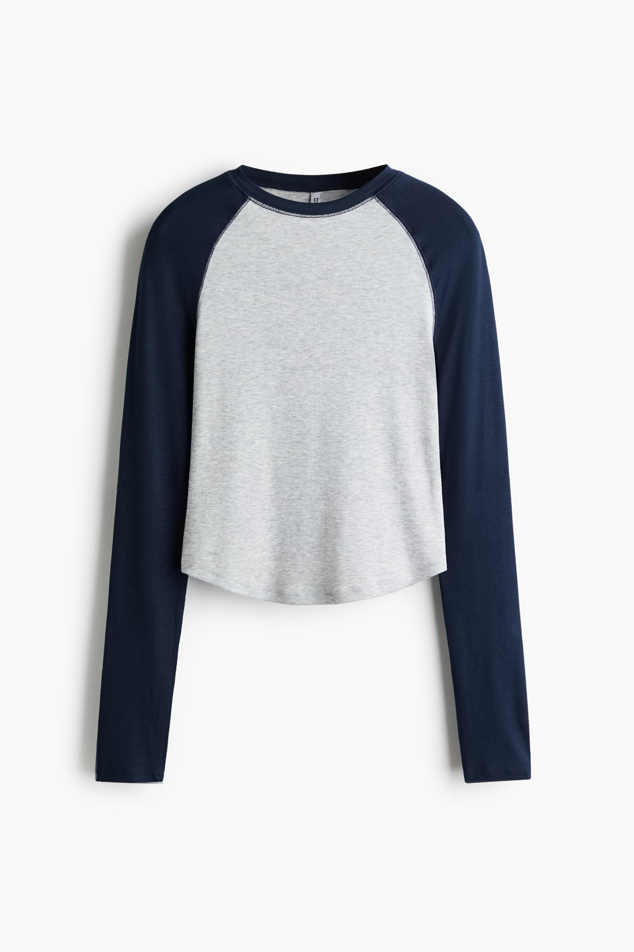 View larger image: A long-sleeved raglan T-shirt is shown from the front, featuring a heather grey body and contrasting navy blue sleeves. The shirt has a crew neck and a curved, slightly cropped hemline.
