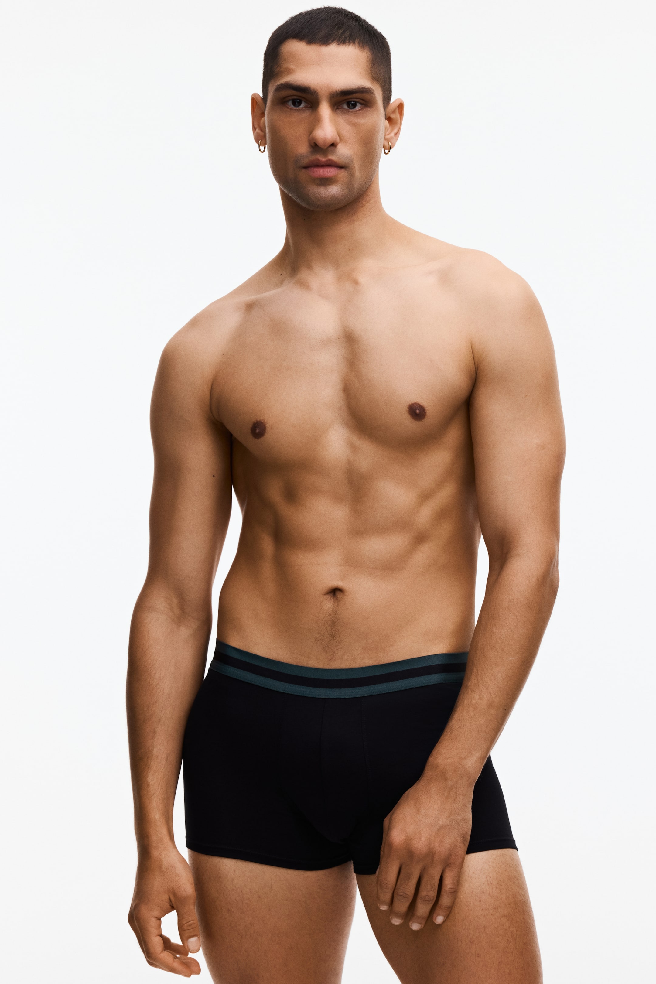 Προβολή μεγαλύτερης εικόνας: Μαύρα μποξεράκια φοριούνται από μπροστινή γωνία, διαθέτοντας ελαστική ζώνη με δύο οριζόντιες ρίγες. Η πάνω ρίγα είναι σκούρο τιρκουάζ, και η κάτω ρίγα είναι ανοιχτό γκρι.