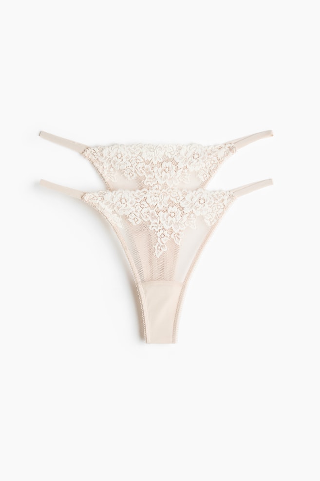 Twee stringslips met een mesh-constructie en kanten afwerkingen, een lage taille, smalle zijkanten en een gevoerd kruisje. Ze worden gepresenteerd met de voorkant naar voren. - 1