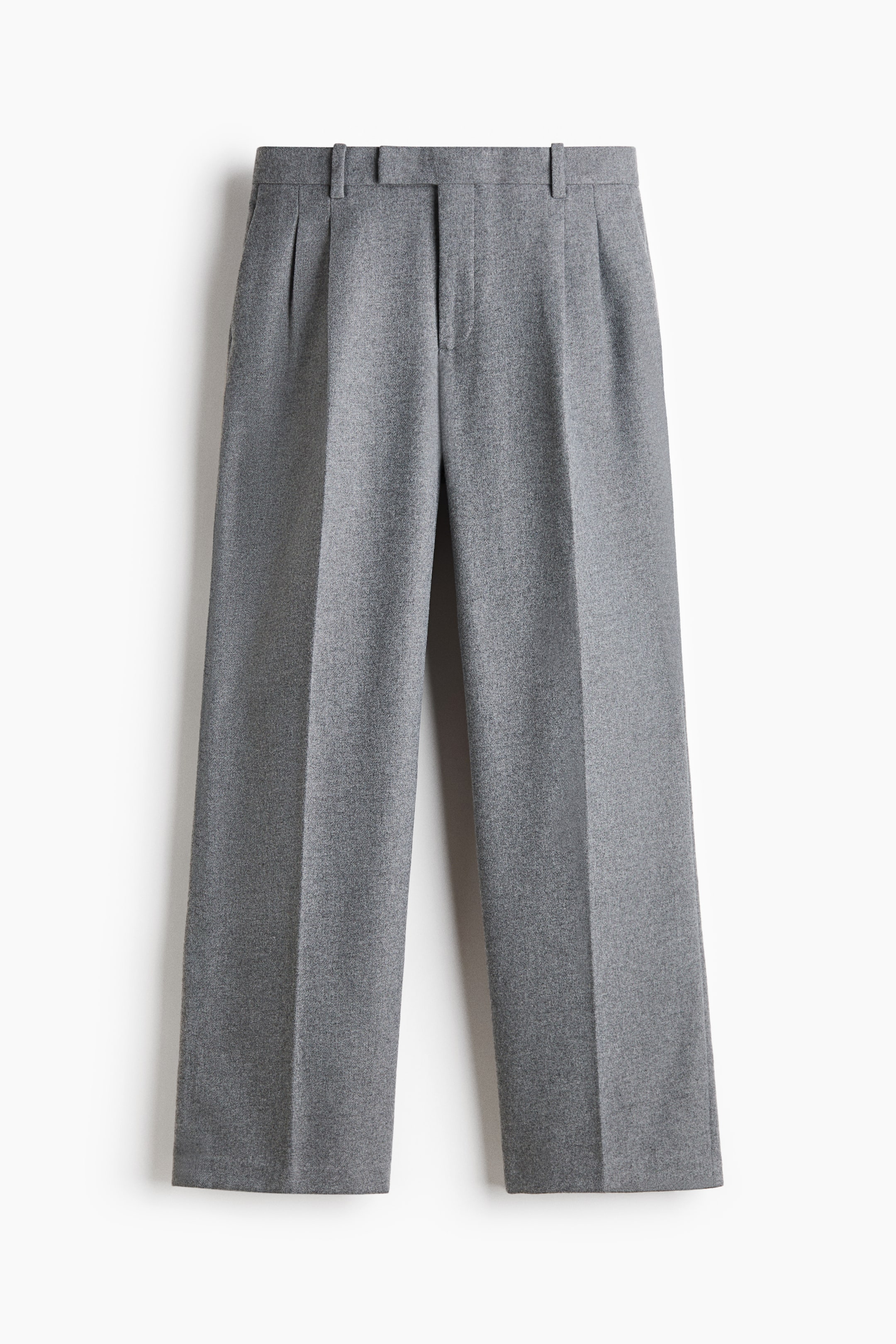 View larger image: Grey trousers are shown from the front, featuring a structured waistband with belt loops and a concealed front fastening. The design features single front pleats and sharp pressed creases running down the centre of the straight, wide legs.