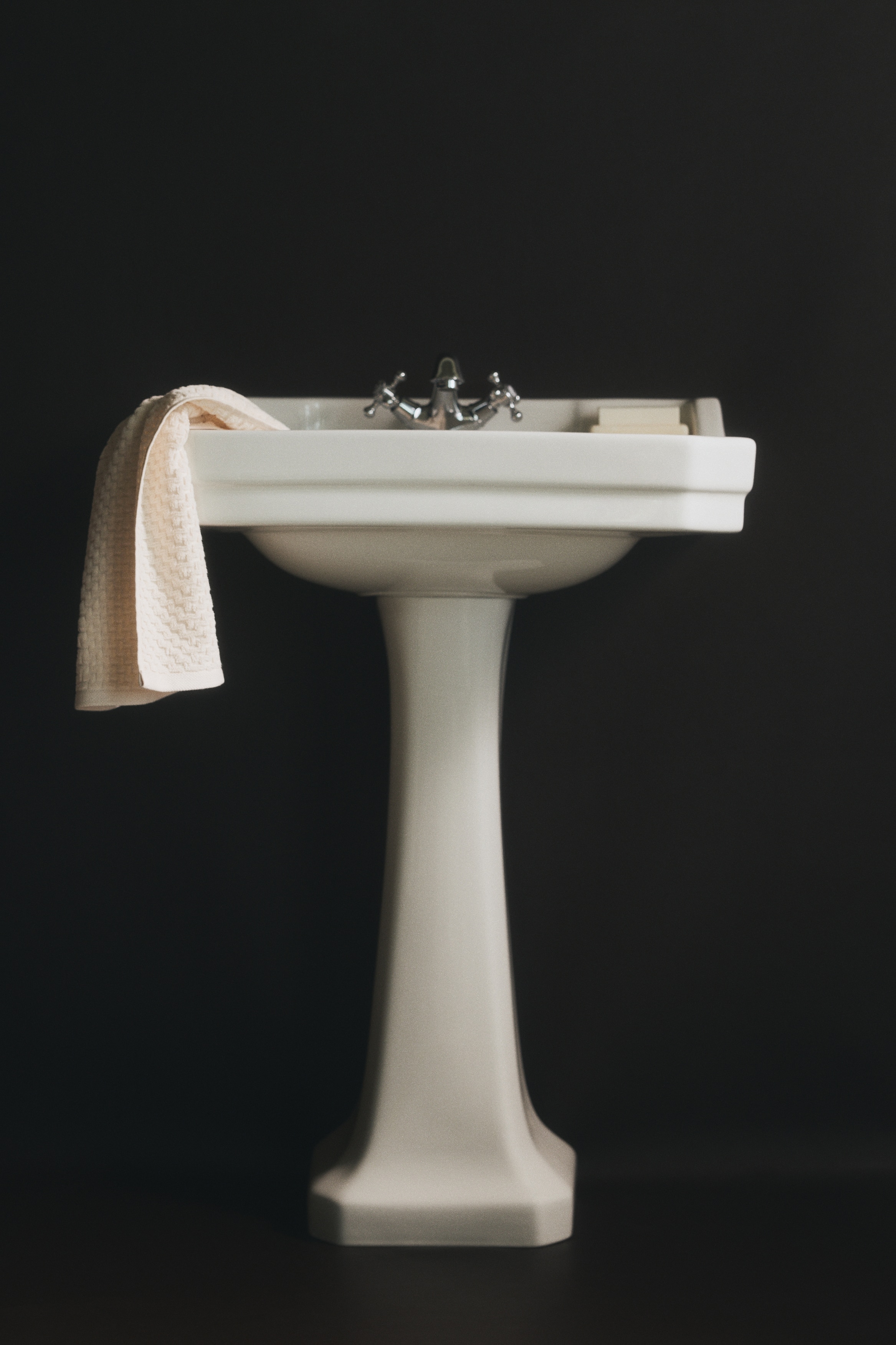 A light-coloured hand towel, featuring a textured zigzag design, is hanging vertically from a black hook.