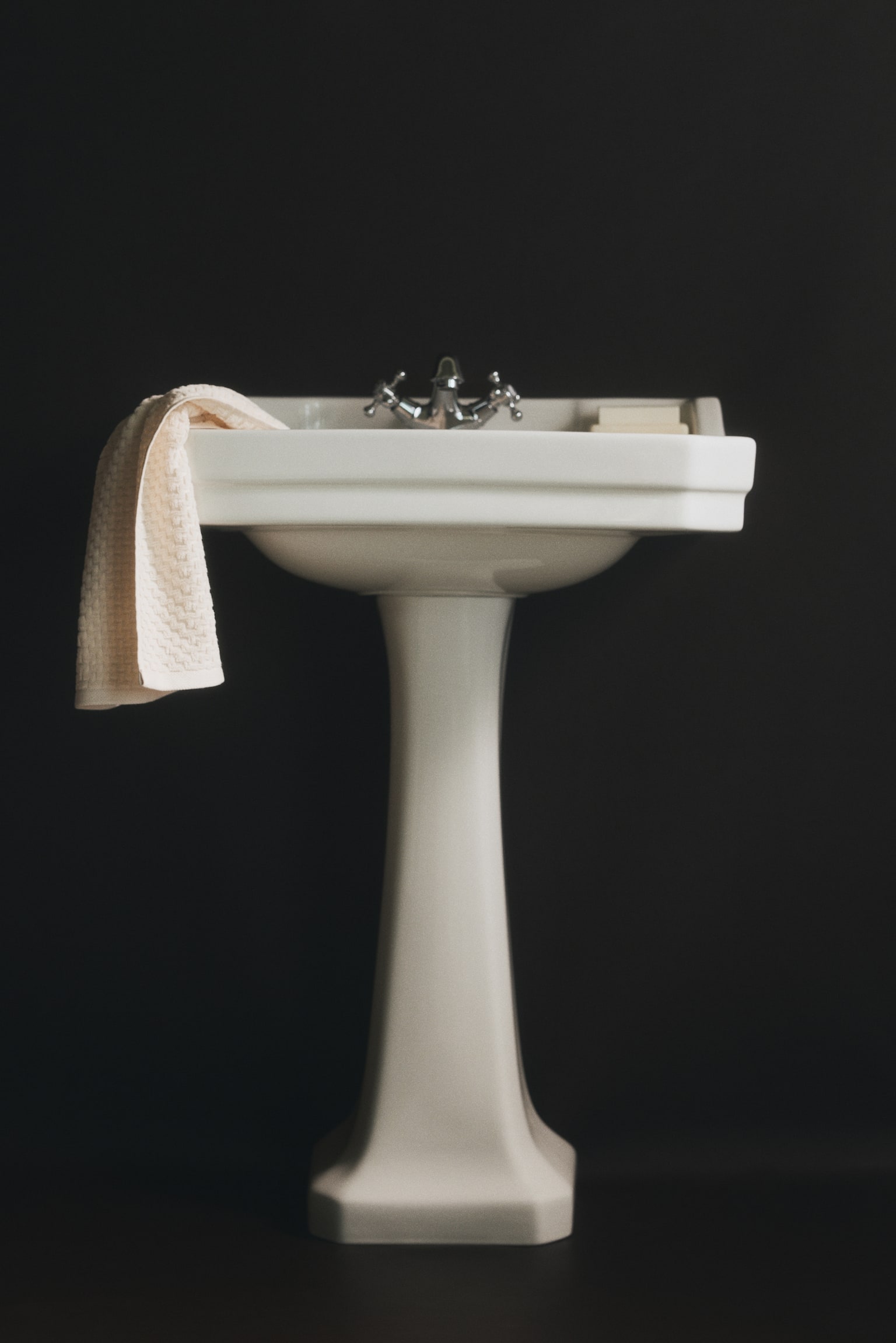 A light-coloured hand towel, featuring a textured zigzag design, is hanging vertically from a black hook. - 1