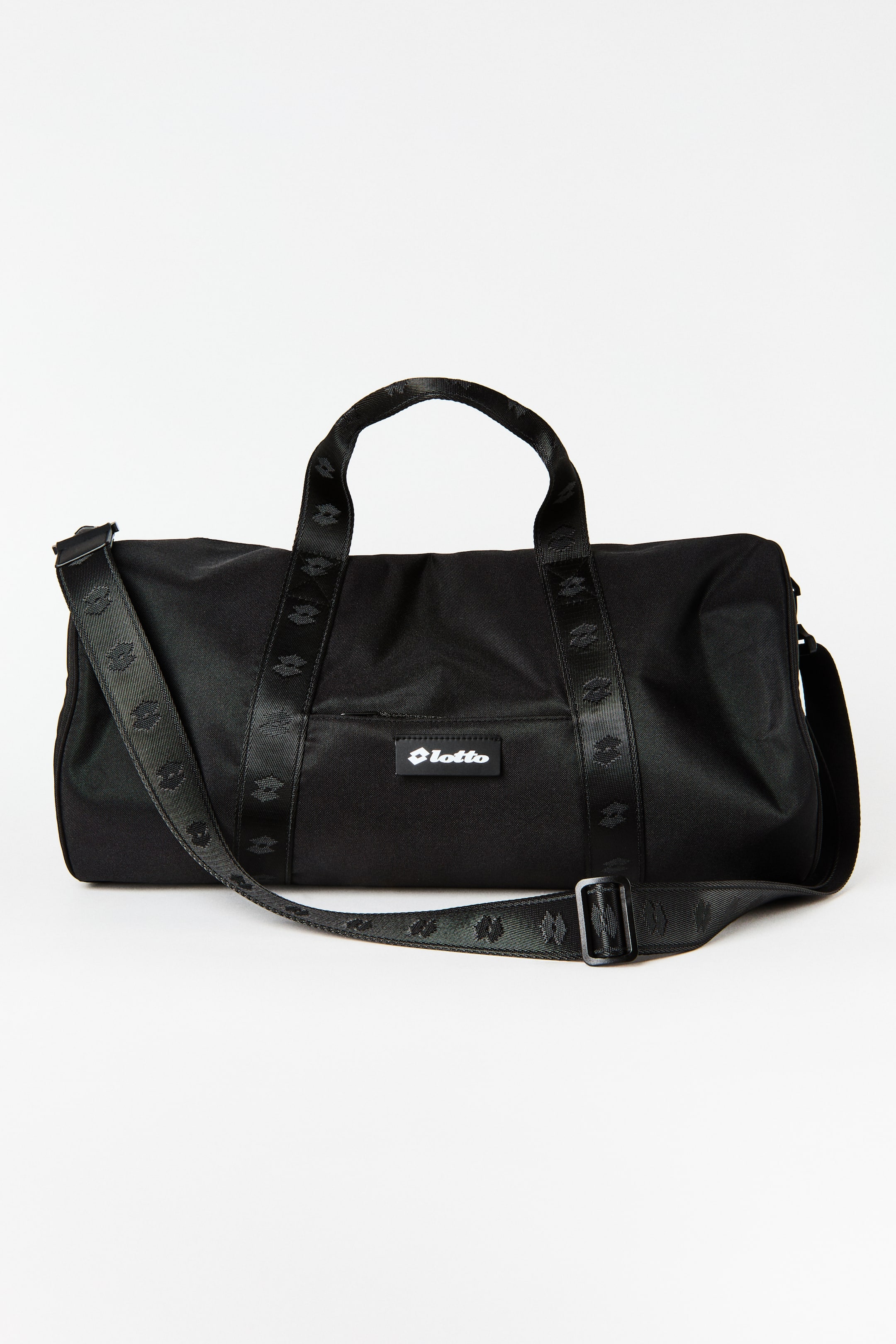 Ampliar la imagen: Se muestra una bolsa de lona negra desde un ángulo ligeramente frontal-derecho, con dos asas superiores para llevar y una correa de hombro desmontable, ambas con un patrón repetido del logo negro. Un parche con el logo blanco de 'Lotto' es visible en la parte frontal.