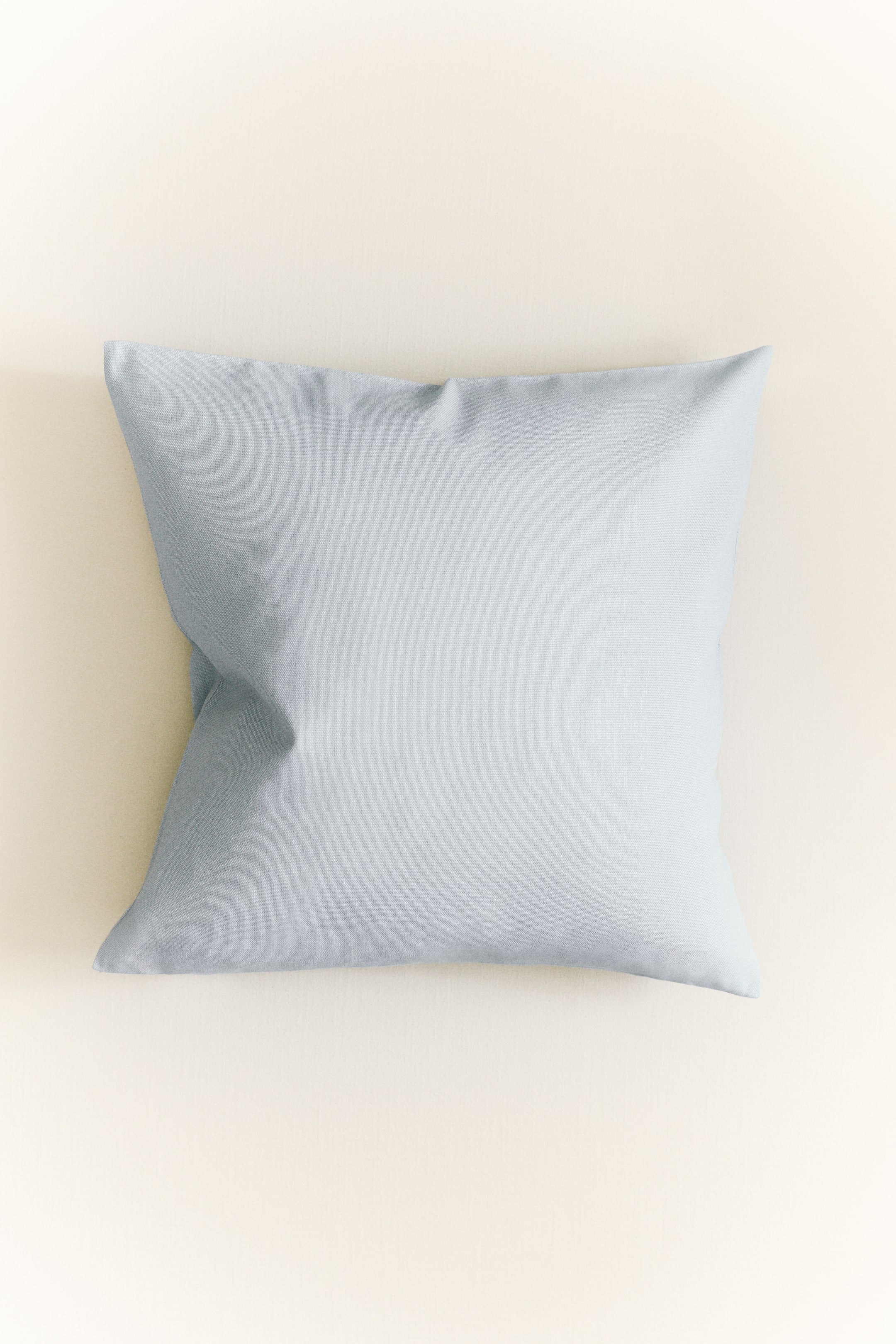 View larger image: A light blue cushion cover is showcasing its front. It boasts a gently plump, square form with a simple woven texture and delicate creases.