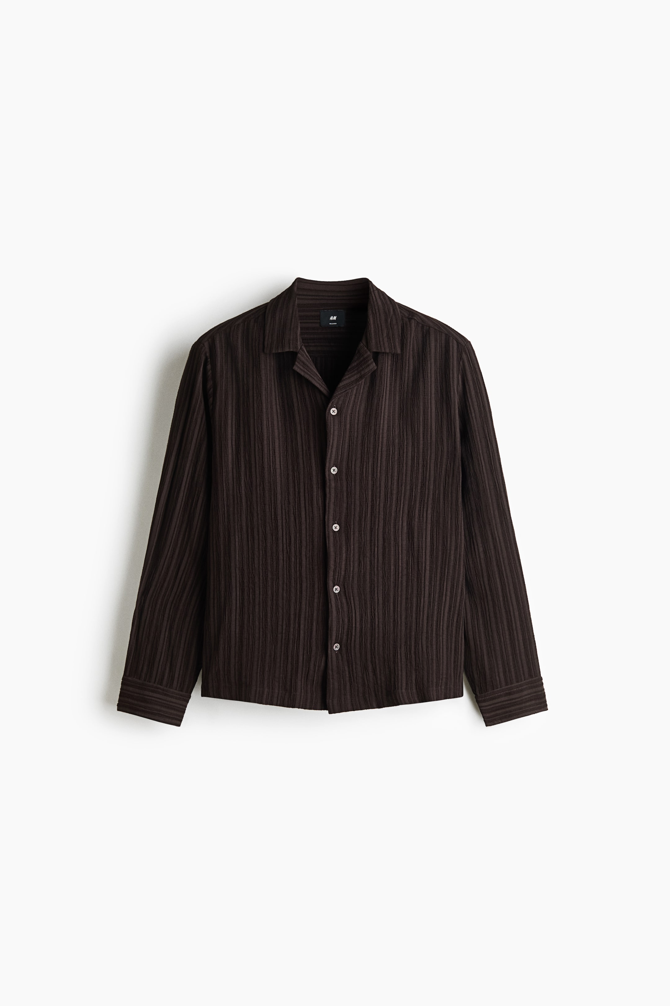 View larger image: A dark brown, long-sleeved shirt featuring vertically textured, crinkled fabric is shown from the front. The shirt has a resort collar, a button-up front with five contrasting light-coloured buttons, and a straight hem.