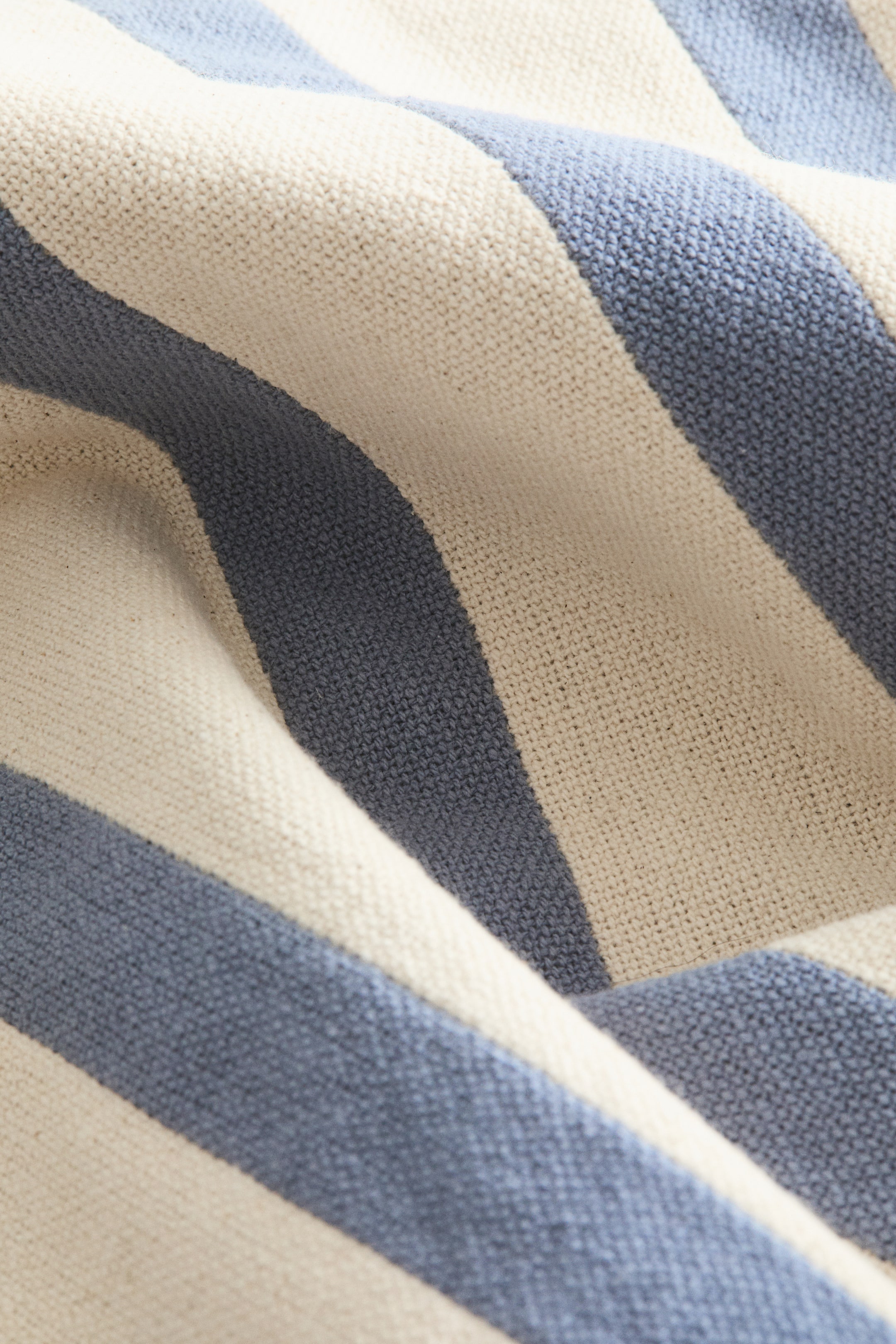 Visualizza l'immagine ingrandita: Un tessuto a maglia presenta strisce alternate bianco sporco e blu tenue. Il tessuto è delicatamente piegato, mettendo in risalto la sua texture visibile.