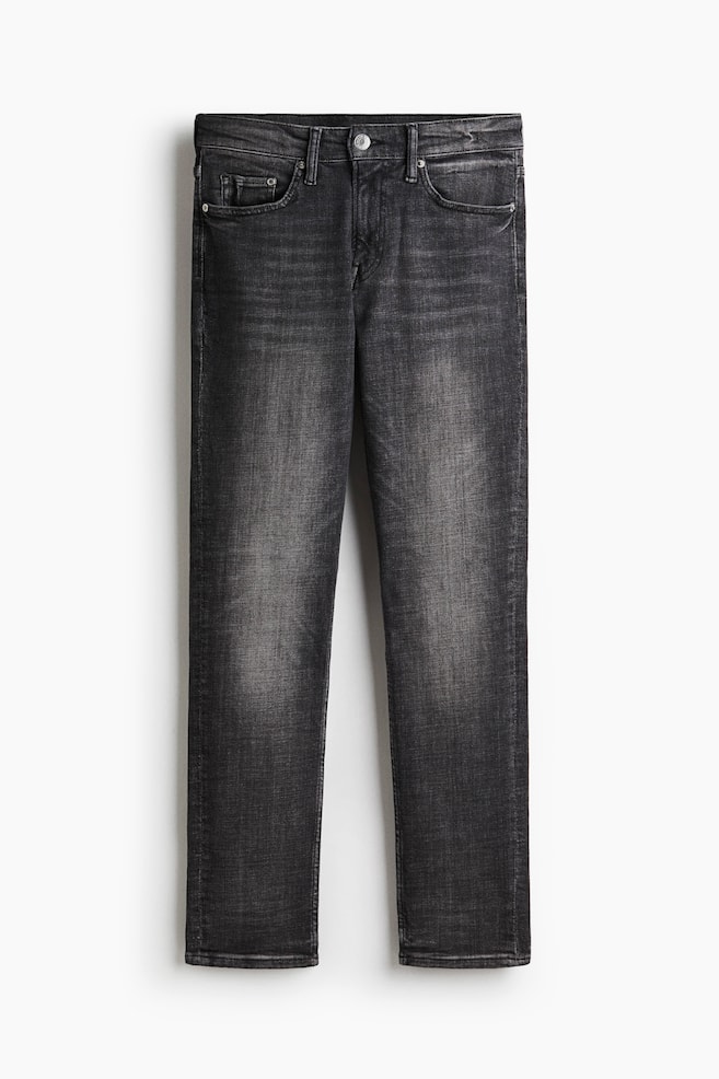 A pair of dark gray, slim-fit jeans is being presented, featuring a straight leg. The FRONT of the jeans is showing a regular waist with a button and zip fly, along with five-pocket styling and a faded wash on the denim. - 1