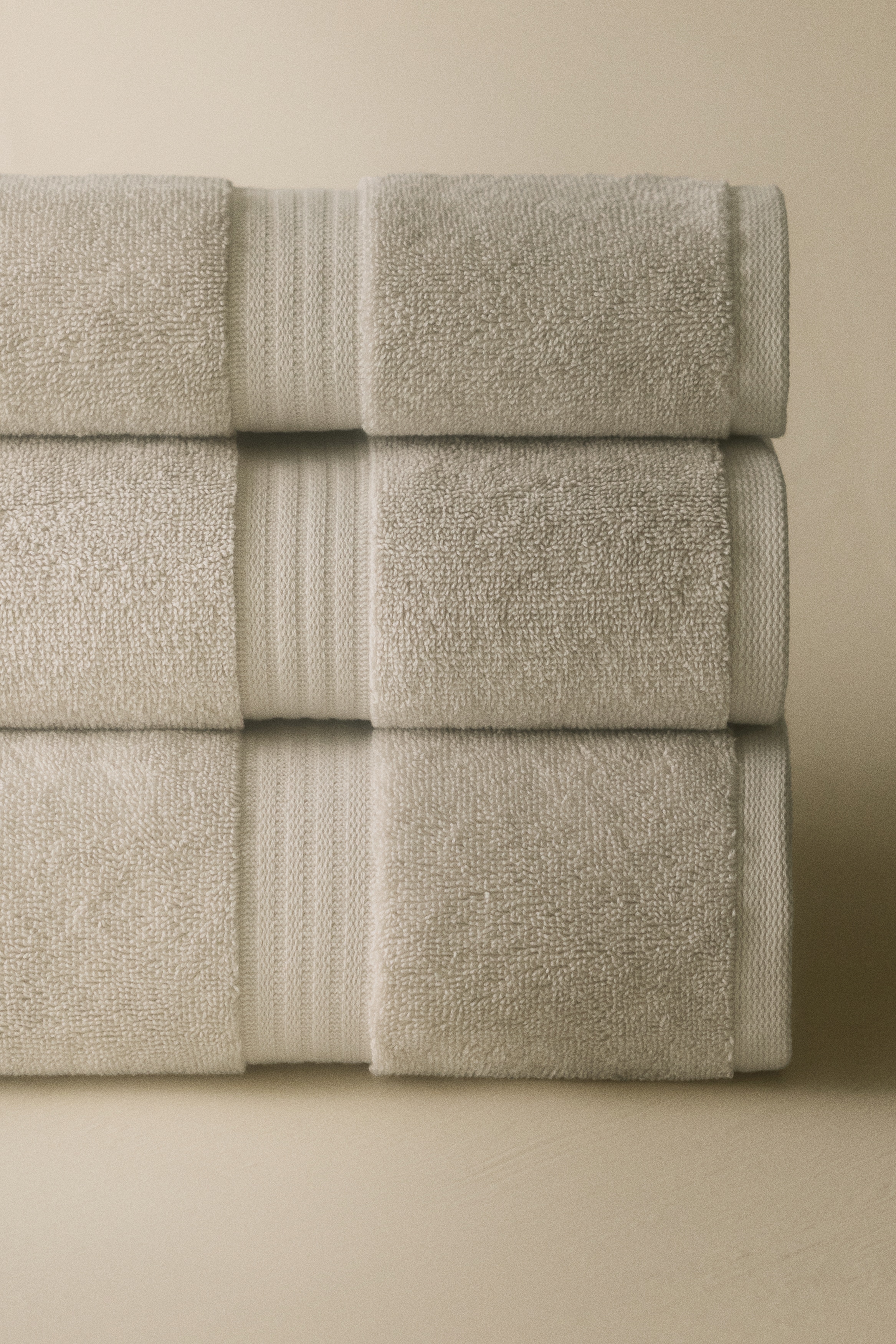 A light grey towel is draped over a hook, featuring subtle horizontal striped bands near its edges.