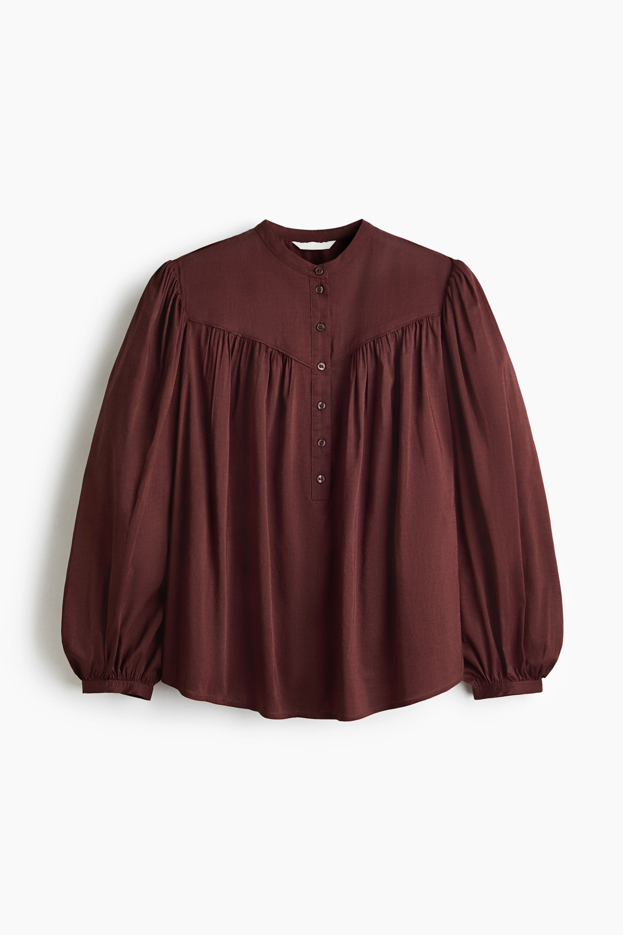 Xem ảnh lớn hơn: Áo blouse dáng rộng bằng vải dệt màu nâu đỏ đậm đang giới thiệu phần TRƯỚC của nó, với cổ áo dạng băng và hàng nút cài một phần. Thiết kế có phần yoke hai lớp và đường may nhún ở phía trước, dẫn đến tay áo dài kiểu bóng với cổ tay áo.