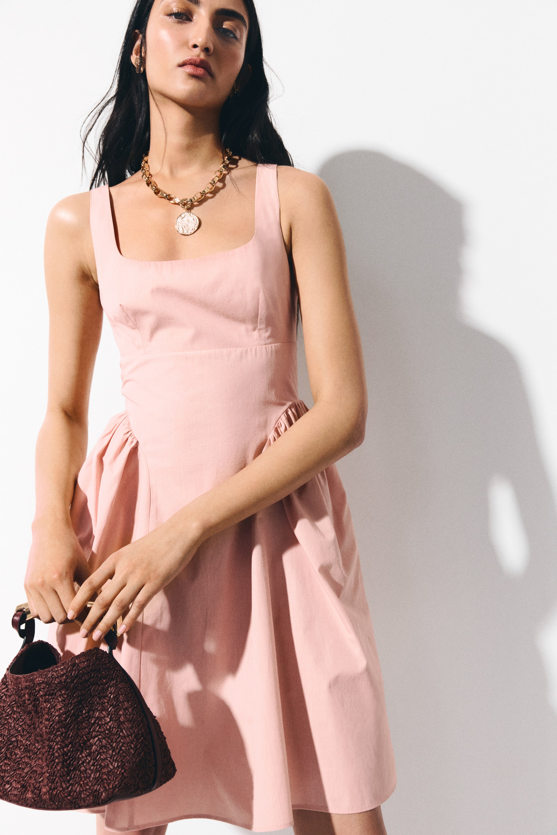 View larger image: The sleeveless pink dress showcases a square neckline and a snug bodice. Its full skirt gathers at the waist, adding volume, as the dress is displayed at a slight angle.