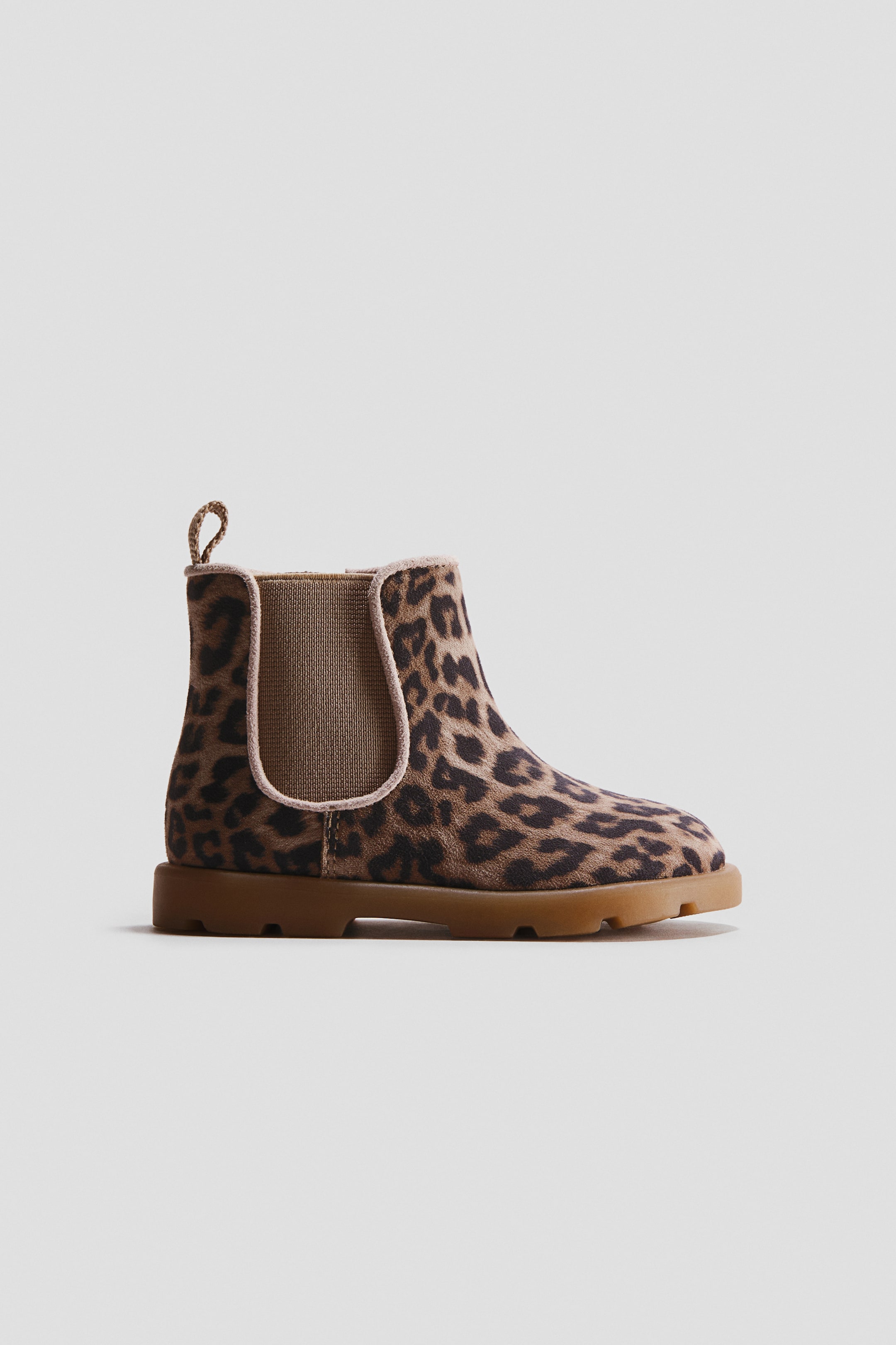 Agrandir l'image: Une seule botte Chelsea est présentée de profil, arborant une tige imprimée léopard marron et noire. Elle est conçue avec un panneau latéral élastique beige, une languette de tirage assortie à l'arrière, et une semelle épaisse marron.