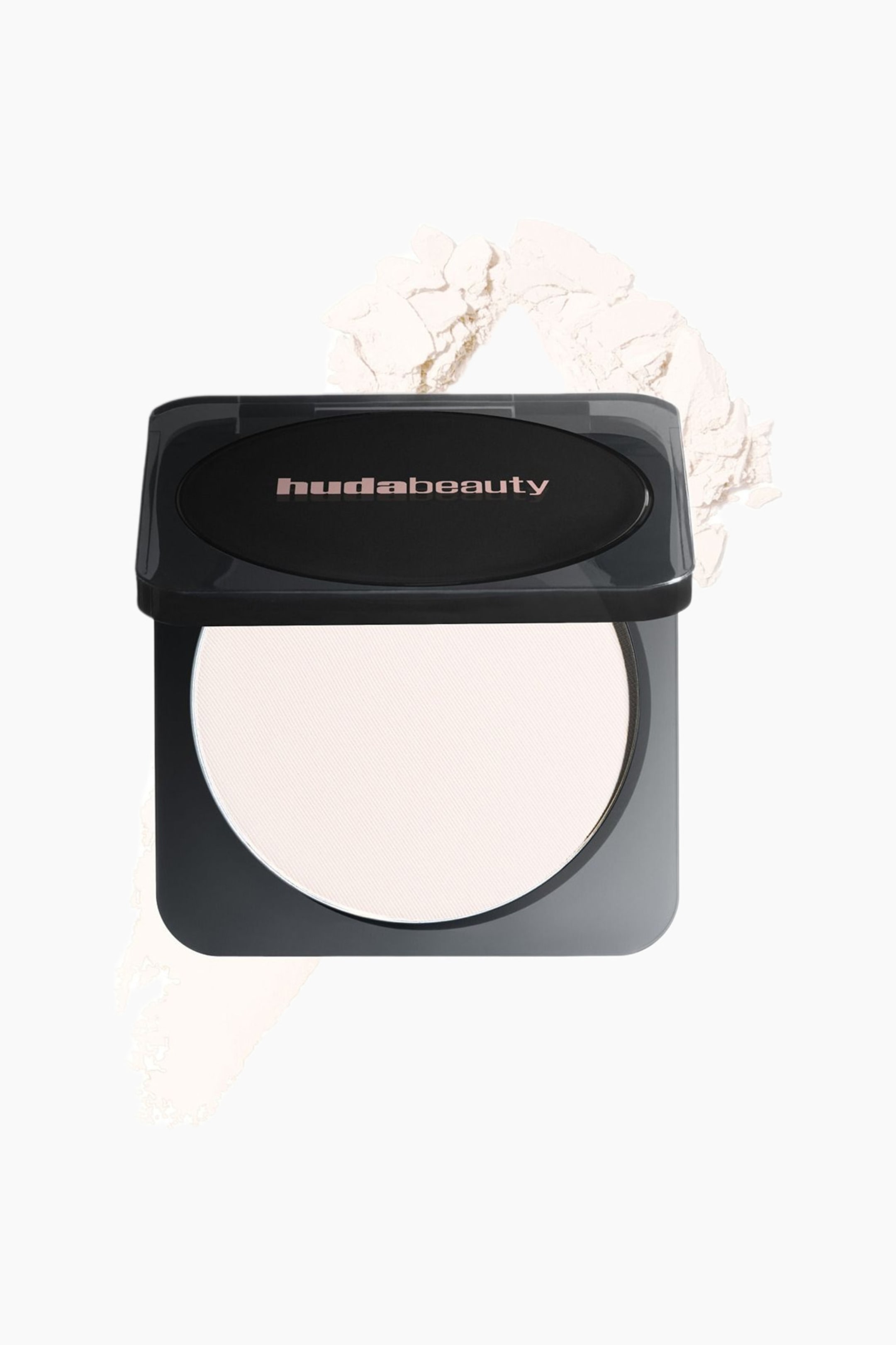 Visa större bild: Ett mörkt kompaktpuder är öppet och visar ett ljusfärgat pressat puder med diskreta diagonala linjer inuti. Kompaktets lock visar varumärket 'hudabeauty' i roséguldsbokstäver på en svart oval insats, och löst puder sprids runt det lätt vinklade kompaktet.