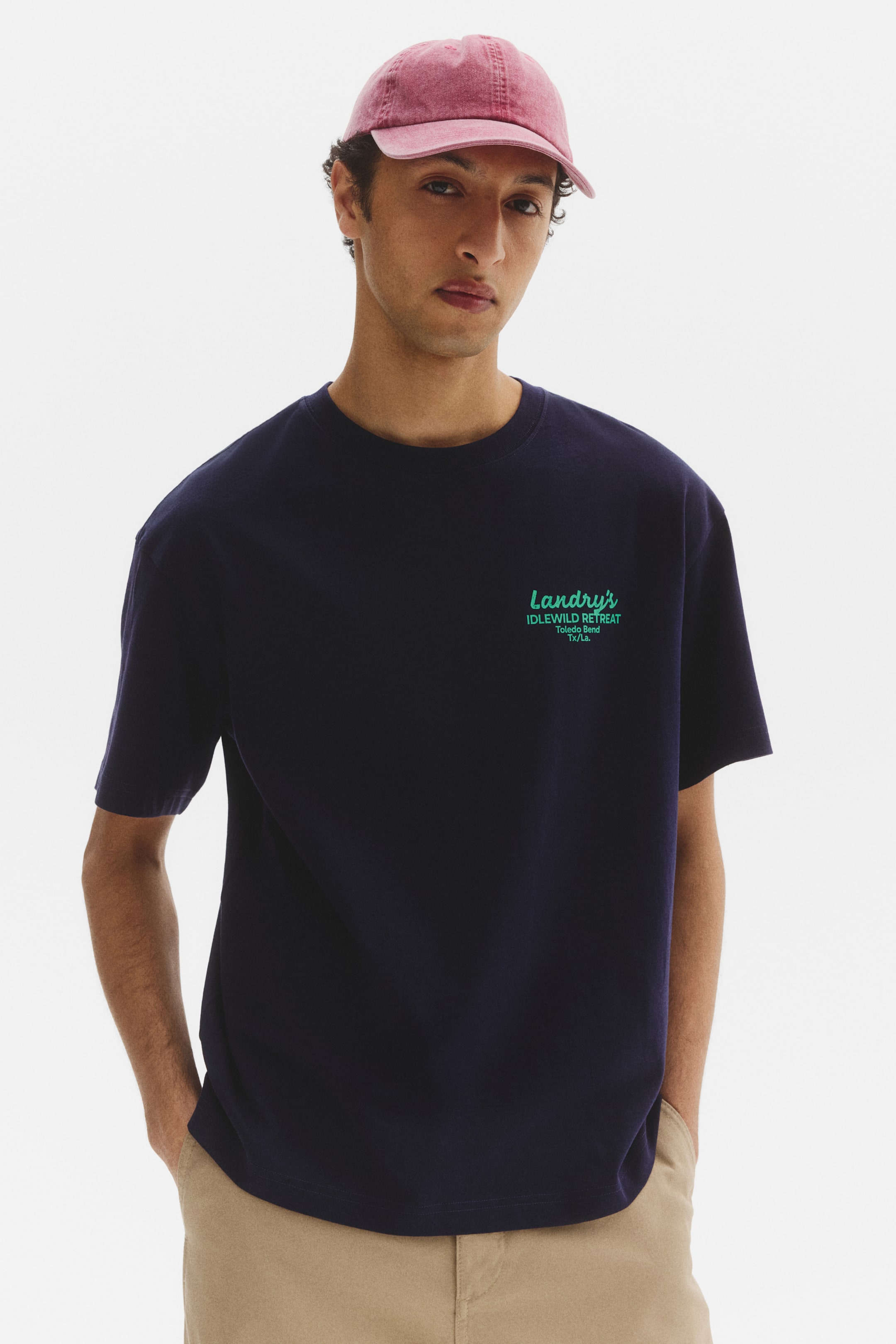 View larger image: Presenting a navy blue short-sleeved t-shirt from a front-facing angle, this piece features a classic crew neck design. On the left chest area, it showcases green text that reads 'Landry's IDLEWILD RETREAT Toledo Bend Tx/La'. Perfect for casual outings or relaxed gatherings.