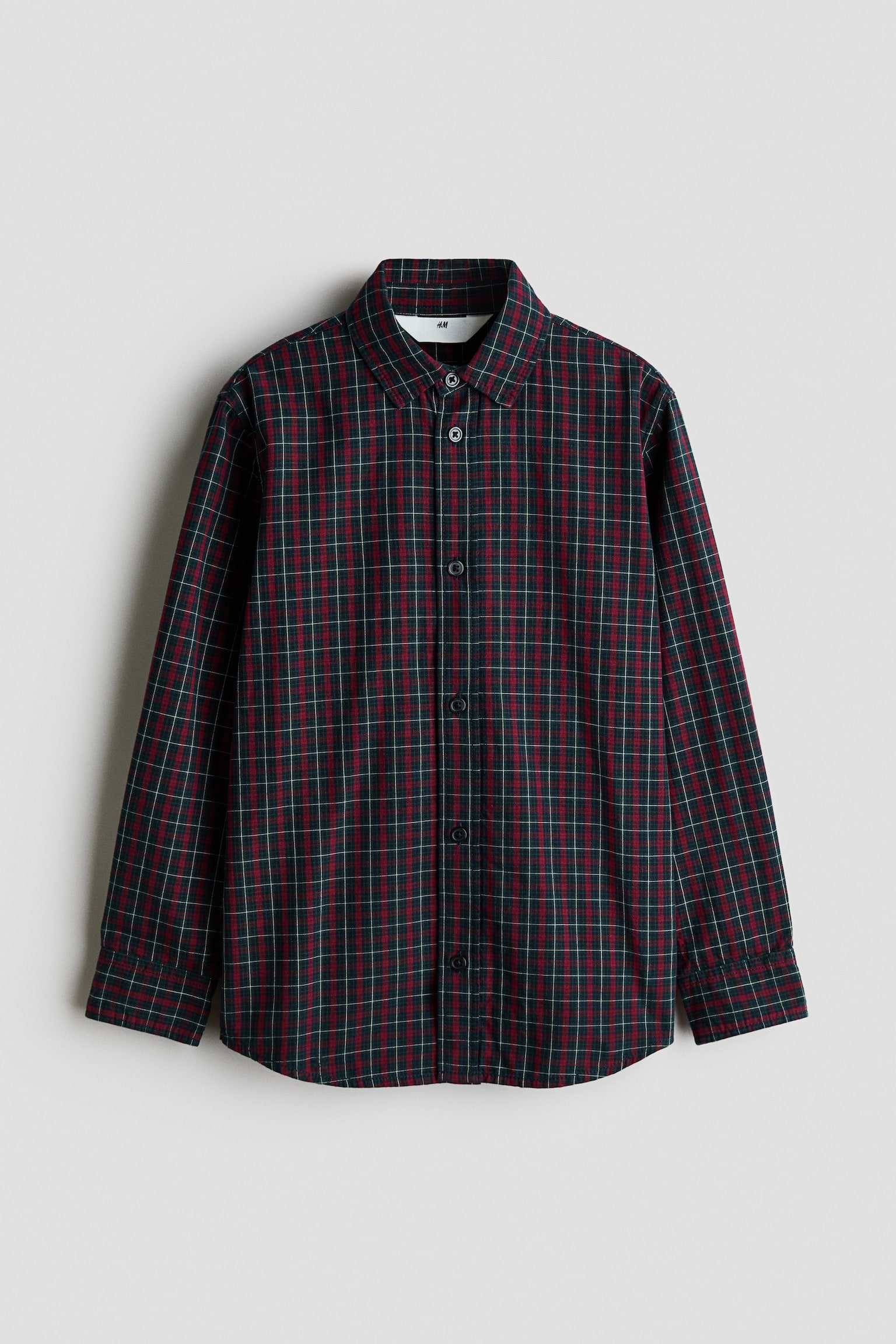 A long-sleeve checked shirt in dark green and red is shown facing front, featuring a turn-down collar, a button-down front, and buttoned cuffs. The shirt is designed with a slightly rounded hem.