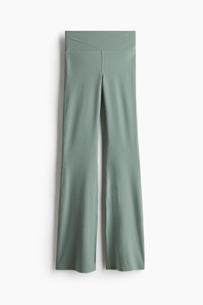 Sage green flare pants are lying flat, presenting a high-rise, wide waistband and a central front seam. The legs are designed with a fitted silhouette through the thigh, flaring out from the knee, and feature vertical seams running down the front of each leg. - 1