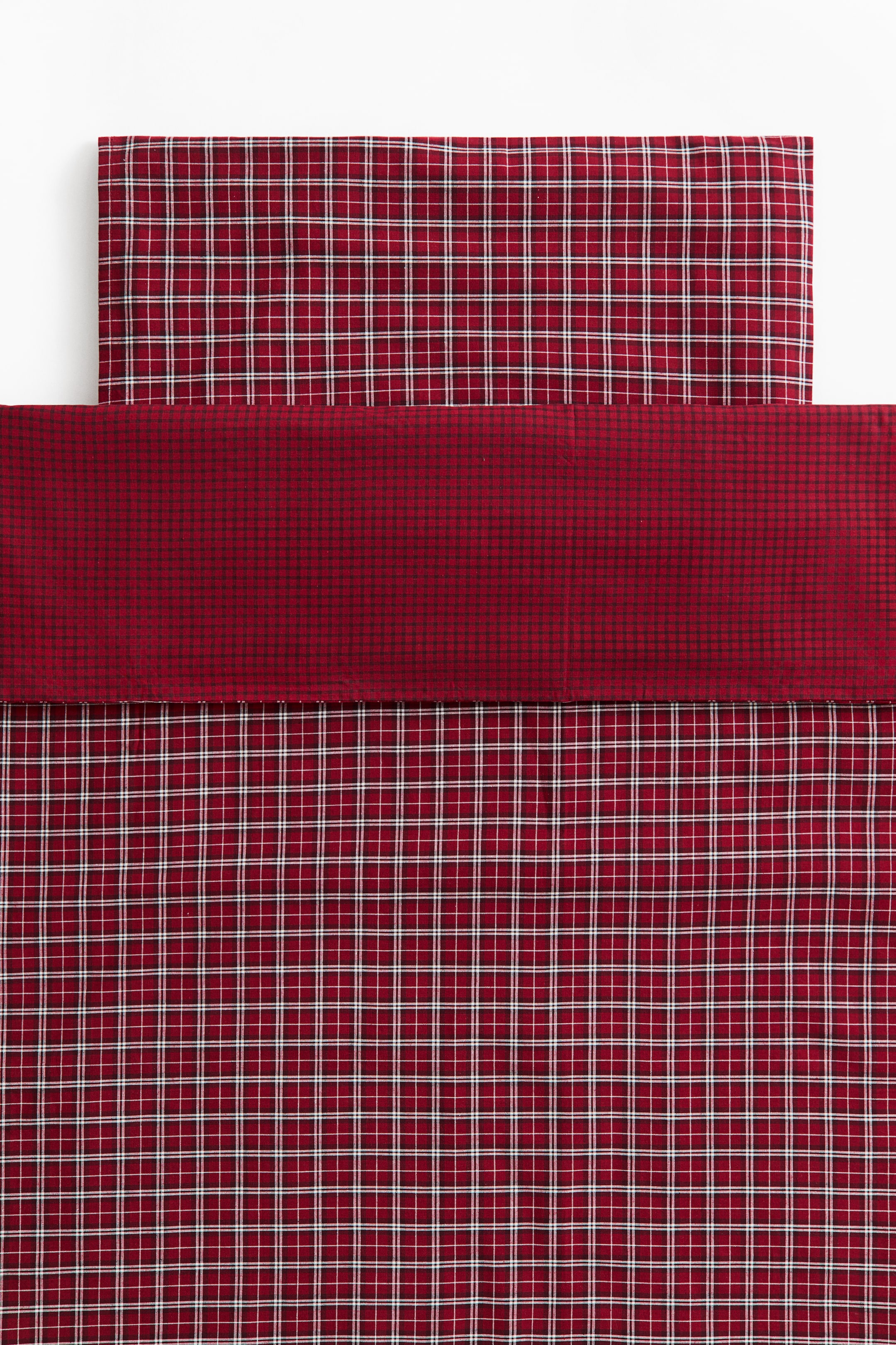 View larger image: A red plaid bedding set is displayed with a matching duvet cover and pillowcase laid flat. The duvet cover features a folded-over top section in a fine, dark red and black micro-check pattern, while the main body and pillowcase display a red, white, and black grid plaid design.