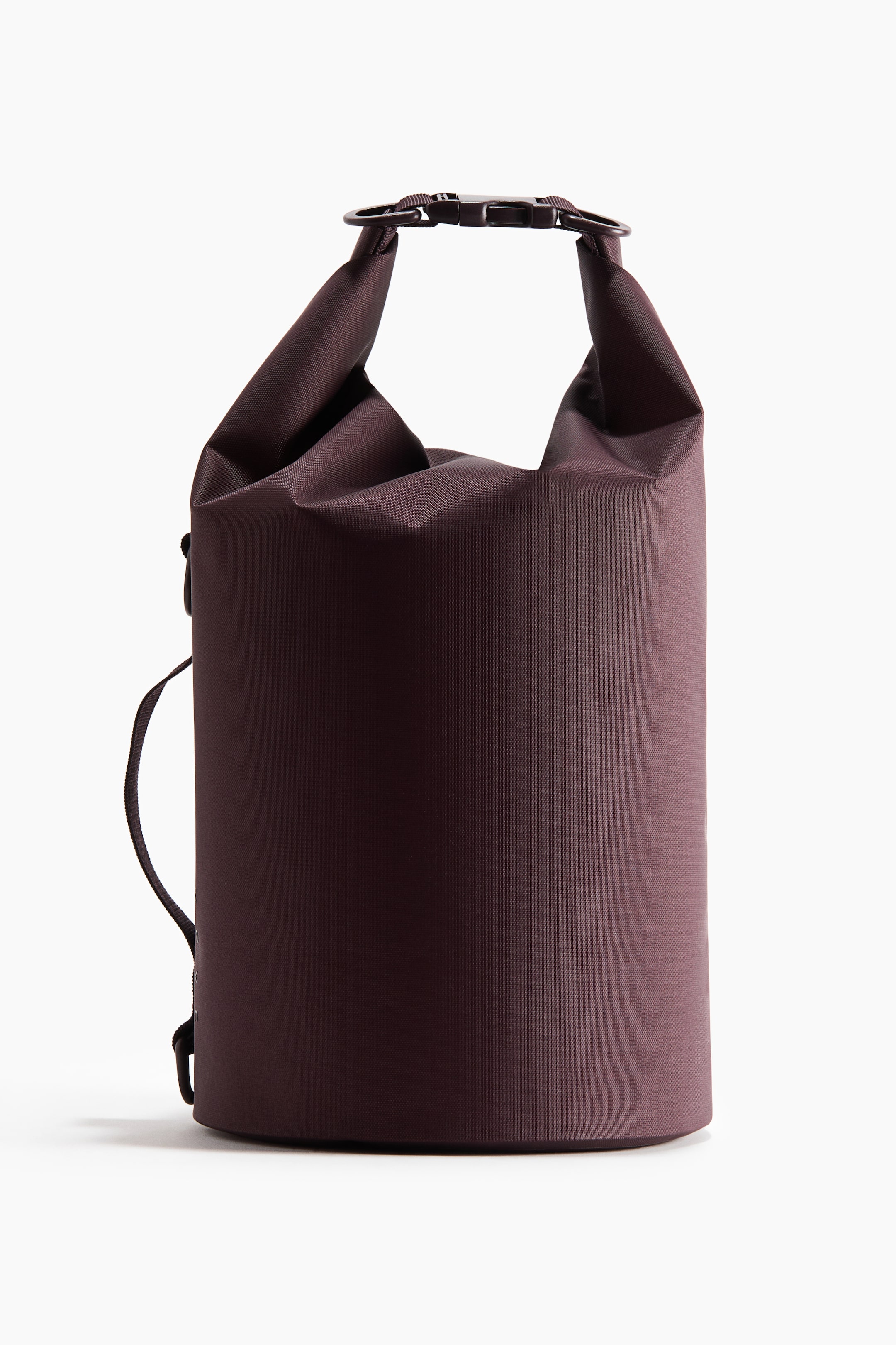 Vezi imaginea mai mare: Un sac impermeabil de culoare prună închisă stă în poziție verticală, având un corp cilindric realizat dintr-un material textil neted și țesut. Partea superioară este rulată și fixată cu o cataramă din plastic închis la culoare, iar o curea subțire neagră se extinde pe partea stângă.