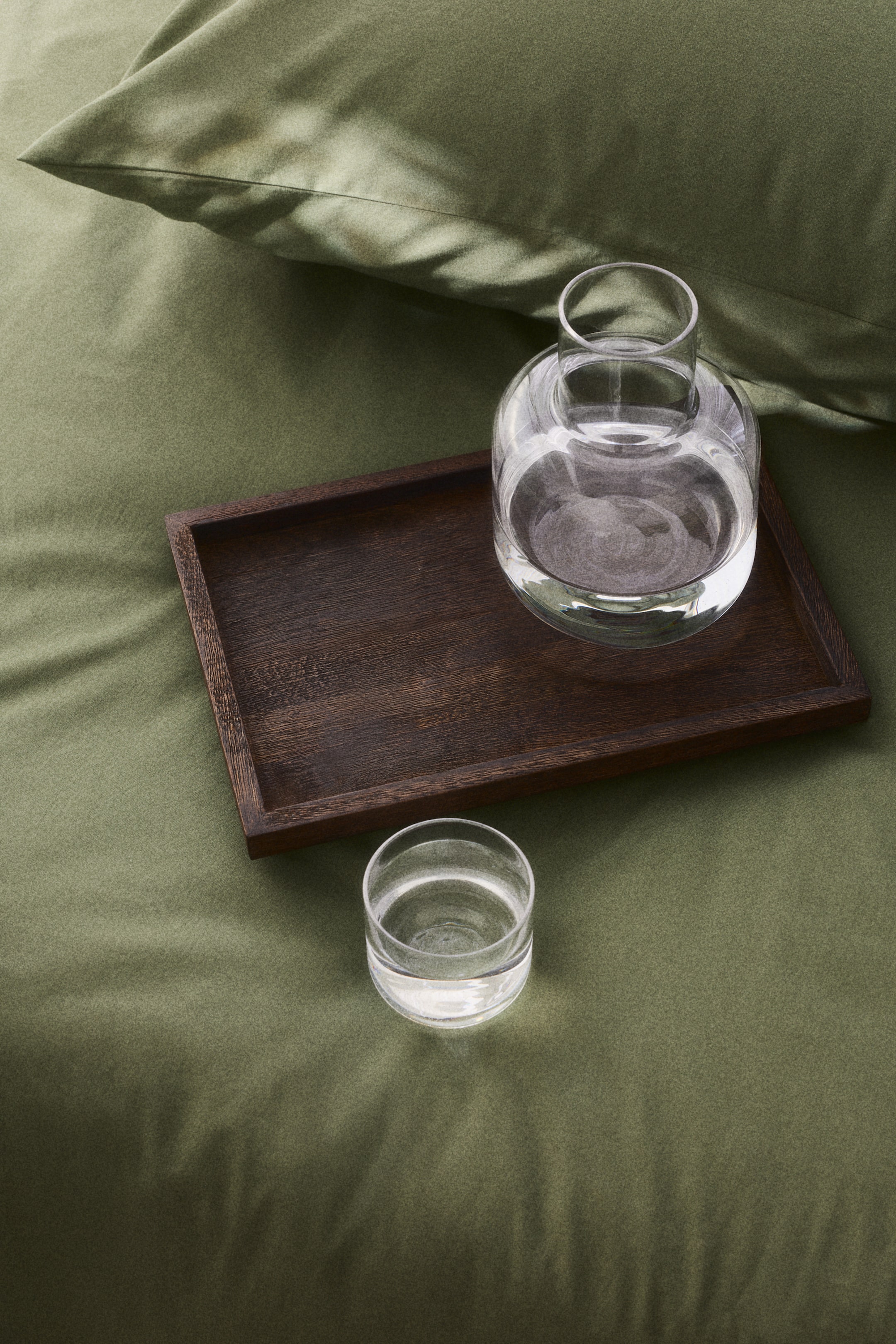 View larger image: A clear glass carafe and a clear glass tumbler, both filled with water, are placed on a dark brown wooden rectangular tray. The tray is set diagonally, highlighting its raised edges.