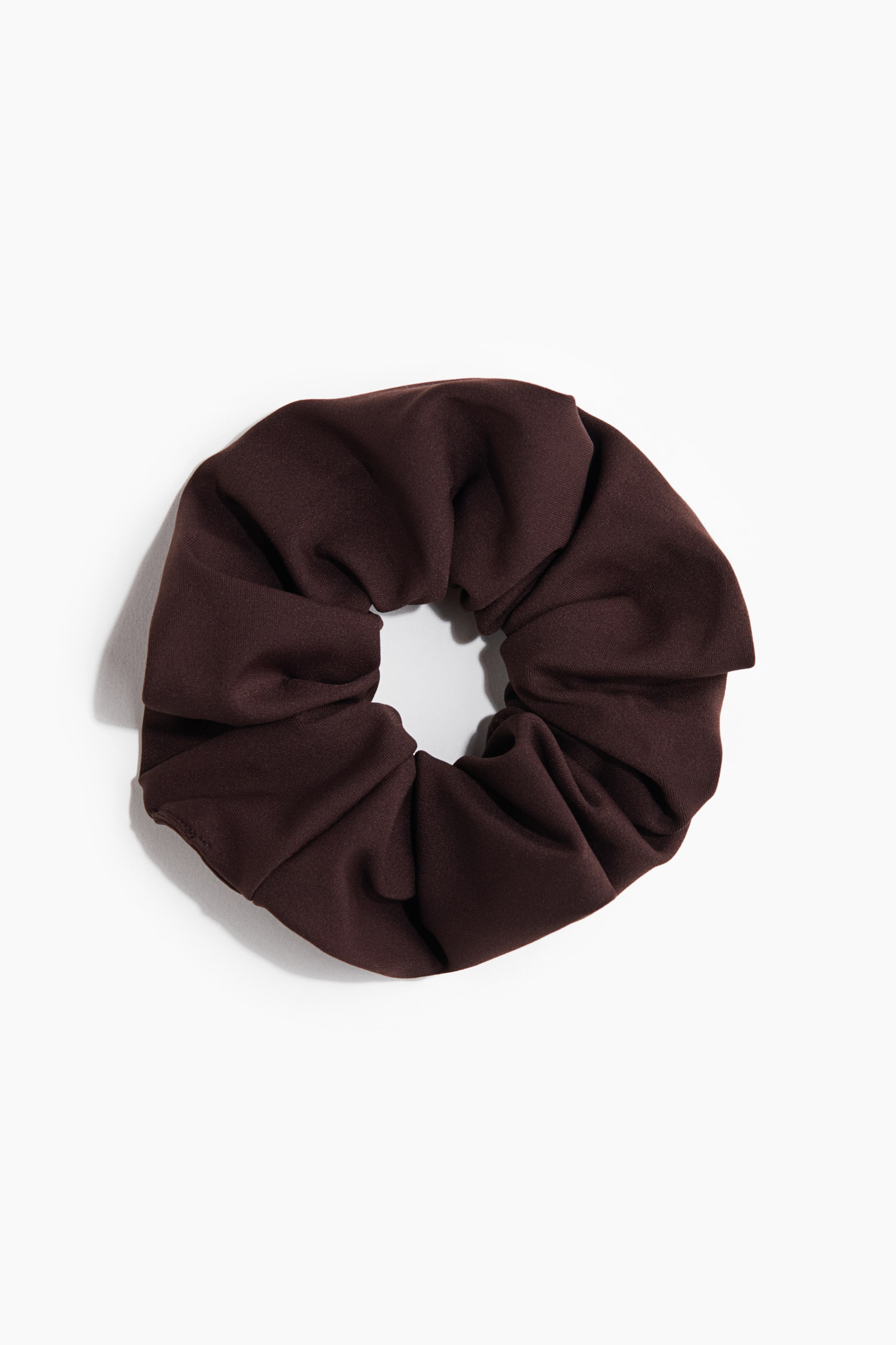 View larger image: A dark brown scrunchie in woven fabric is lying flat, showcasing its gathered and voluminous form.